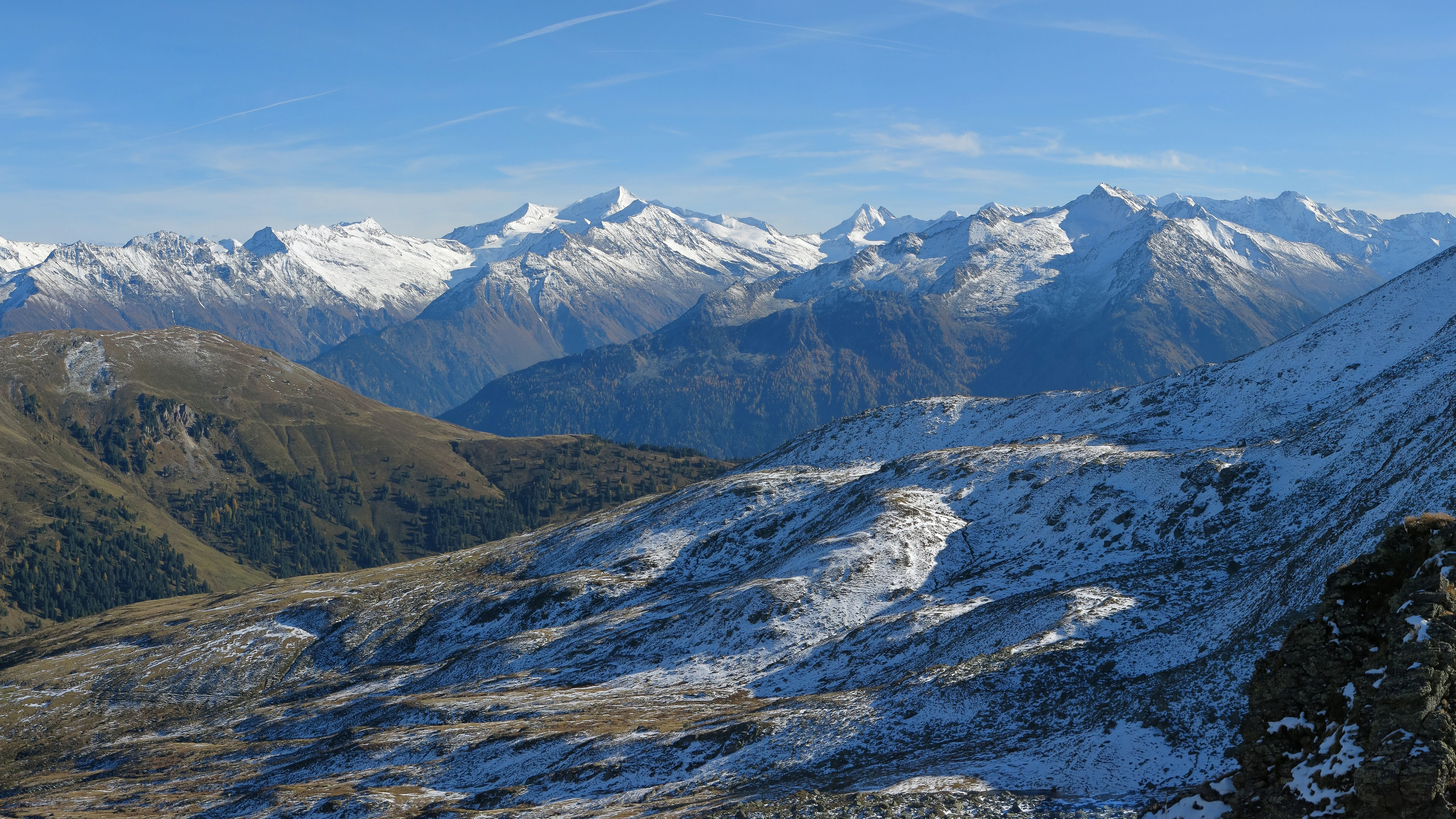 Snow-covered mountain peaks and valleys in Hohe Tauern National Park, Austria under a clear blue sky