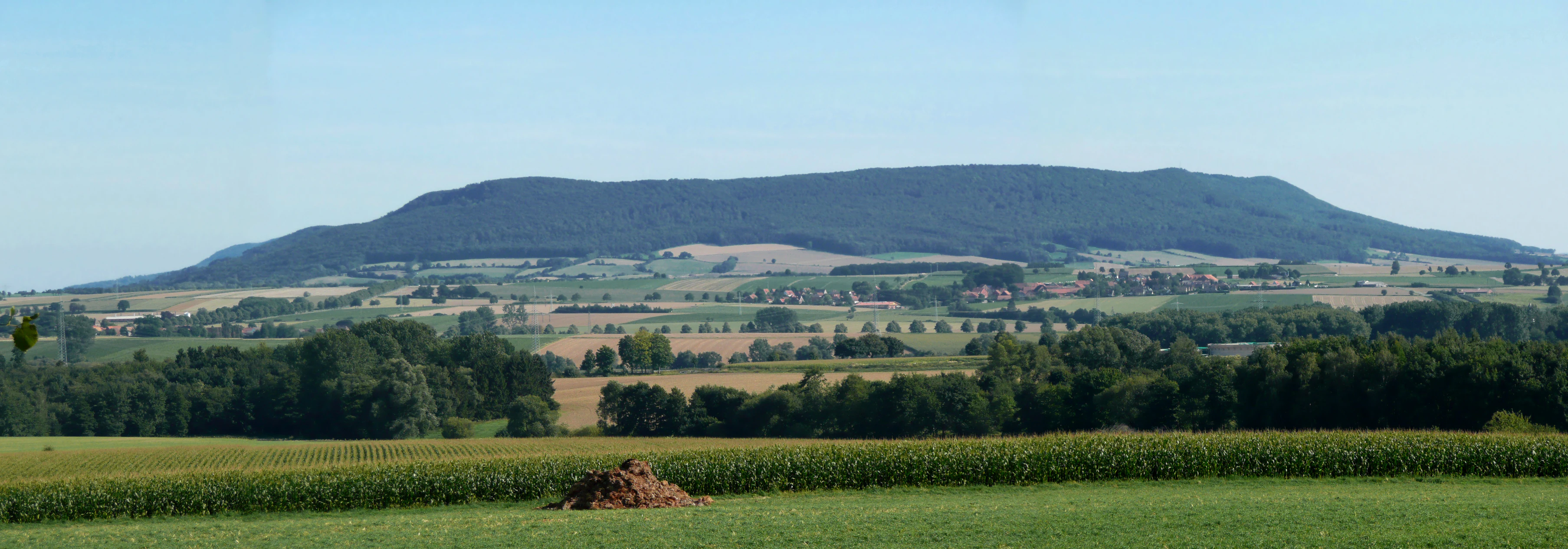 A distant view of the forested Ith mountain ridge rising above a patchwork of rural fields and farmland.