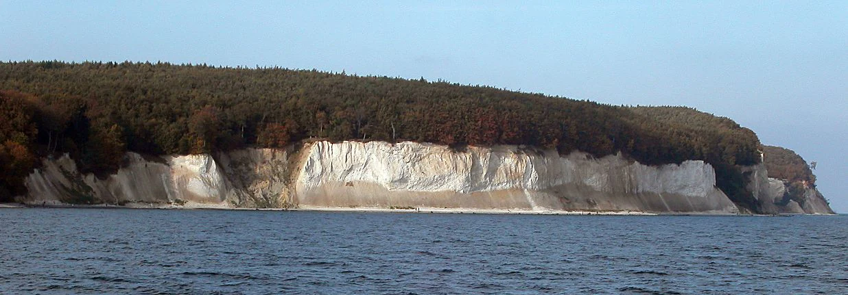 Chalk cliffs along the coast with forested hills and water