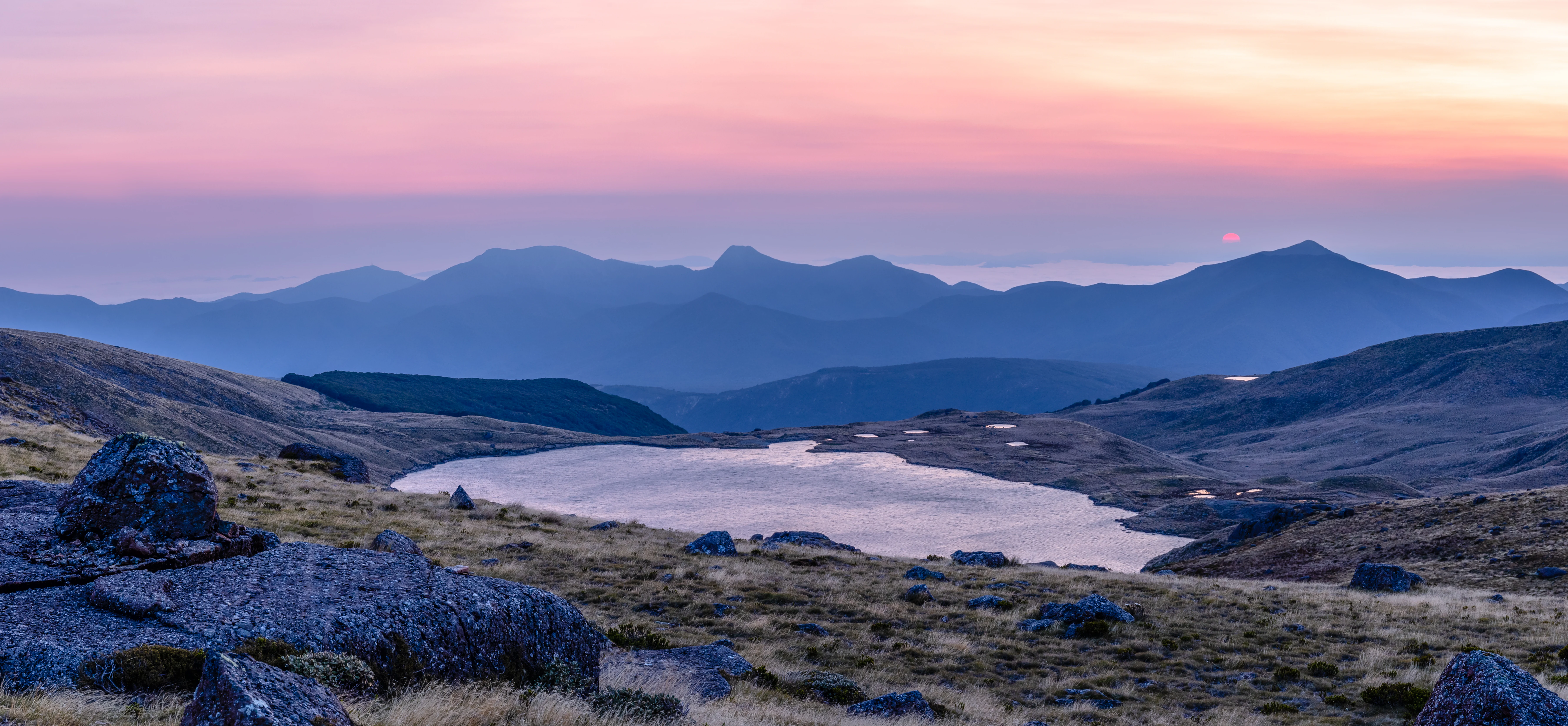 Amanecer sobre el lago Sylvester con cordilleras al fondo bajo un cielo rosa y morado