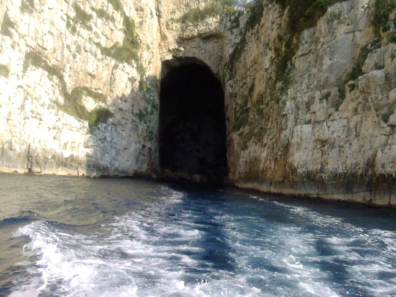 Rocky cliffs with a dark cave entrance opening to the sea