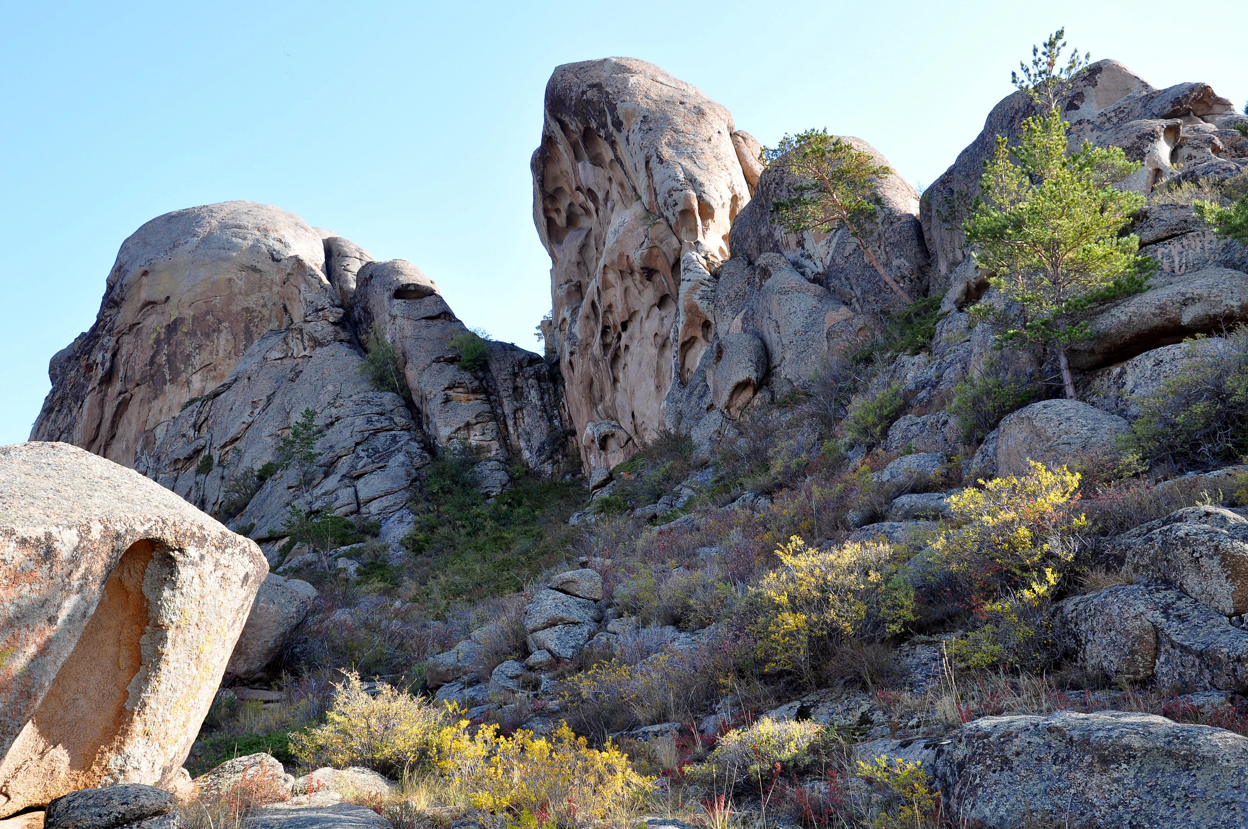 Large rocky formations with sparse vegetation under a clear blue sky