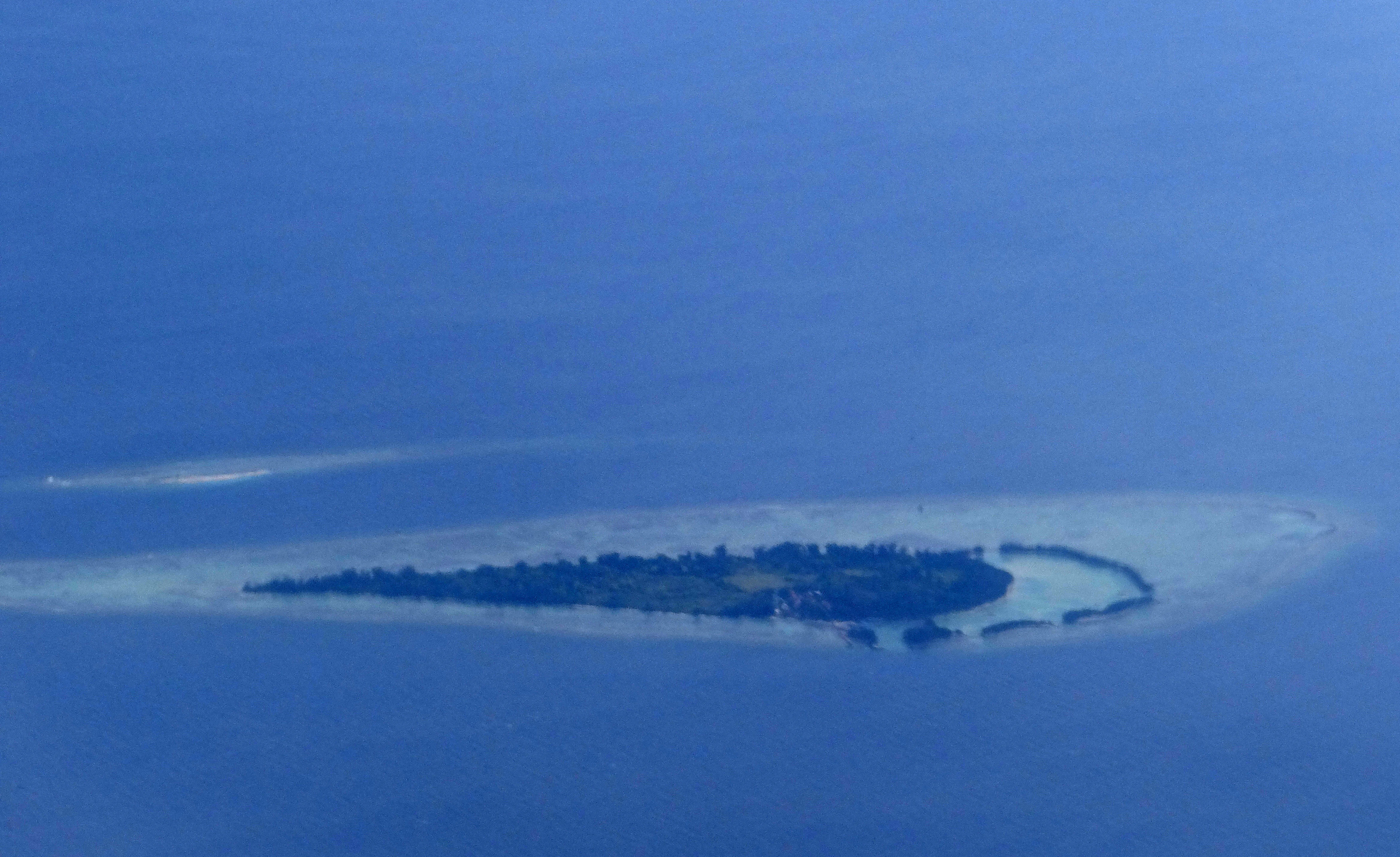 Aerial view of Payung Besar Island surrounded by blue water with a sandy shoreline and small vegetation