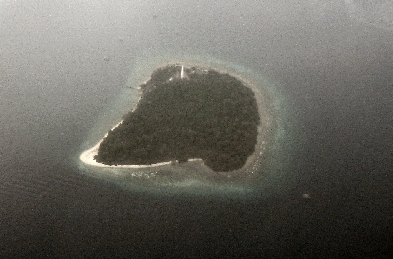 Aerial view of a small island with dense vegetation surrounded by turquoise water