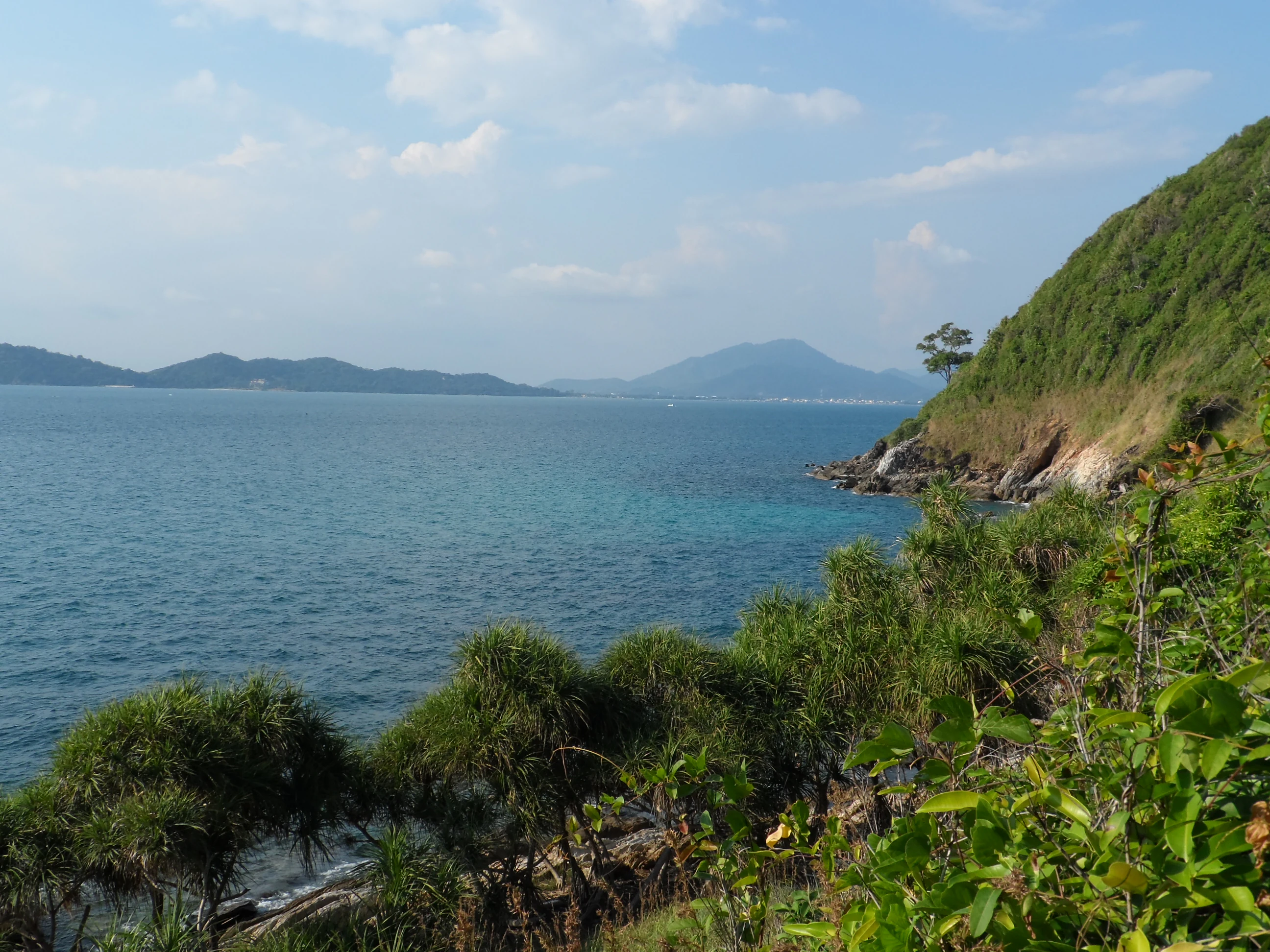Aguas oceánicas turquesas a lo largo de la costa oeste de Ko Samet, con vegetación verde y colinas al fondo