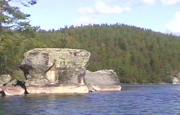Large rock formations in a lake with forested hills in the background