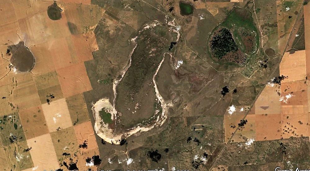 Top-down satellite view of a salt lake with surrounding agricultural landscape and smaller bodies of water in Kazakhstan.