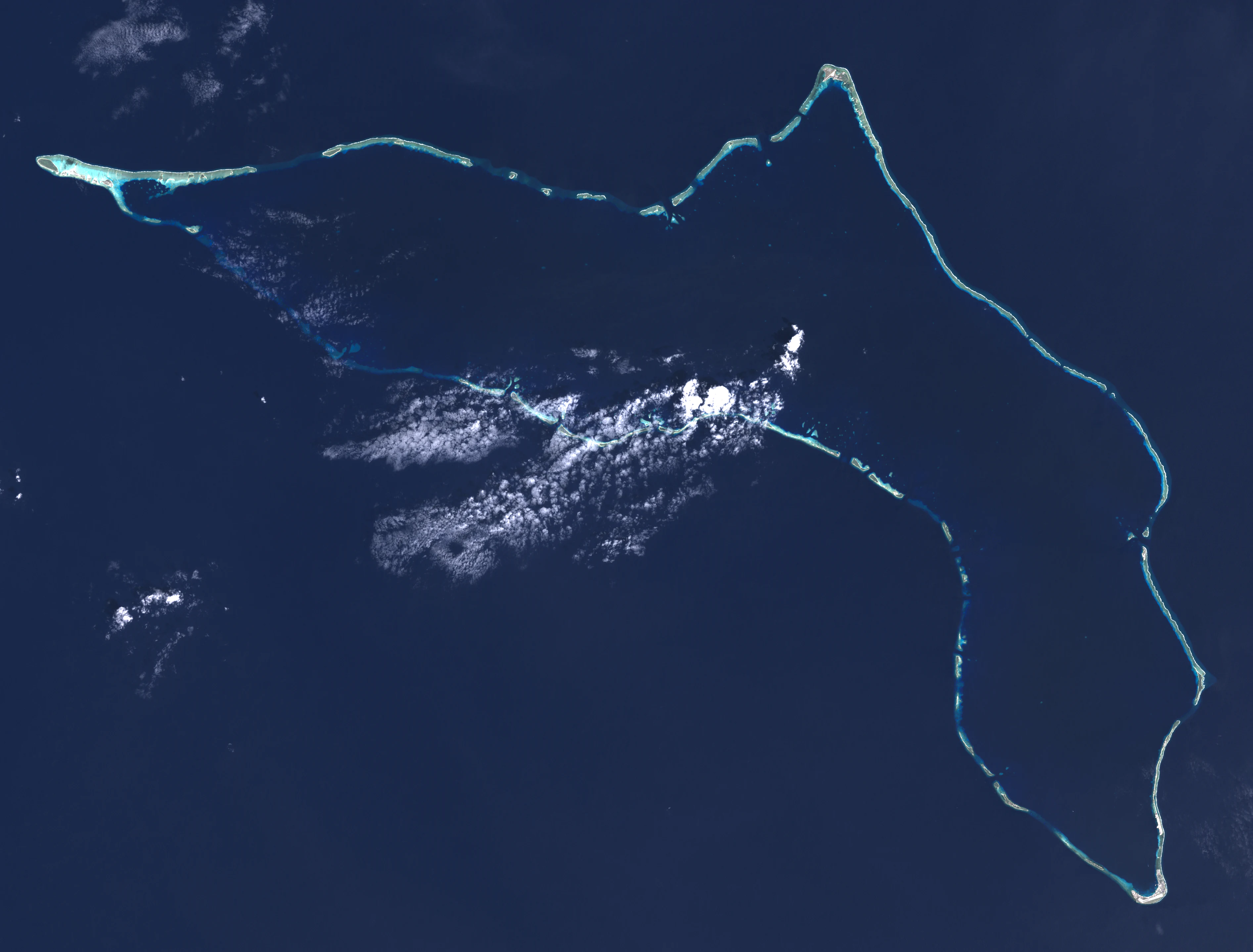 Imagen satelital cenital del atolón Kwajalein que muestra el anillo de arrecife de coral rodeado por aguas oceánicas profundas.