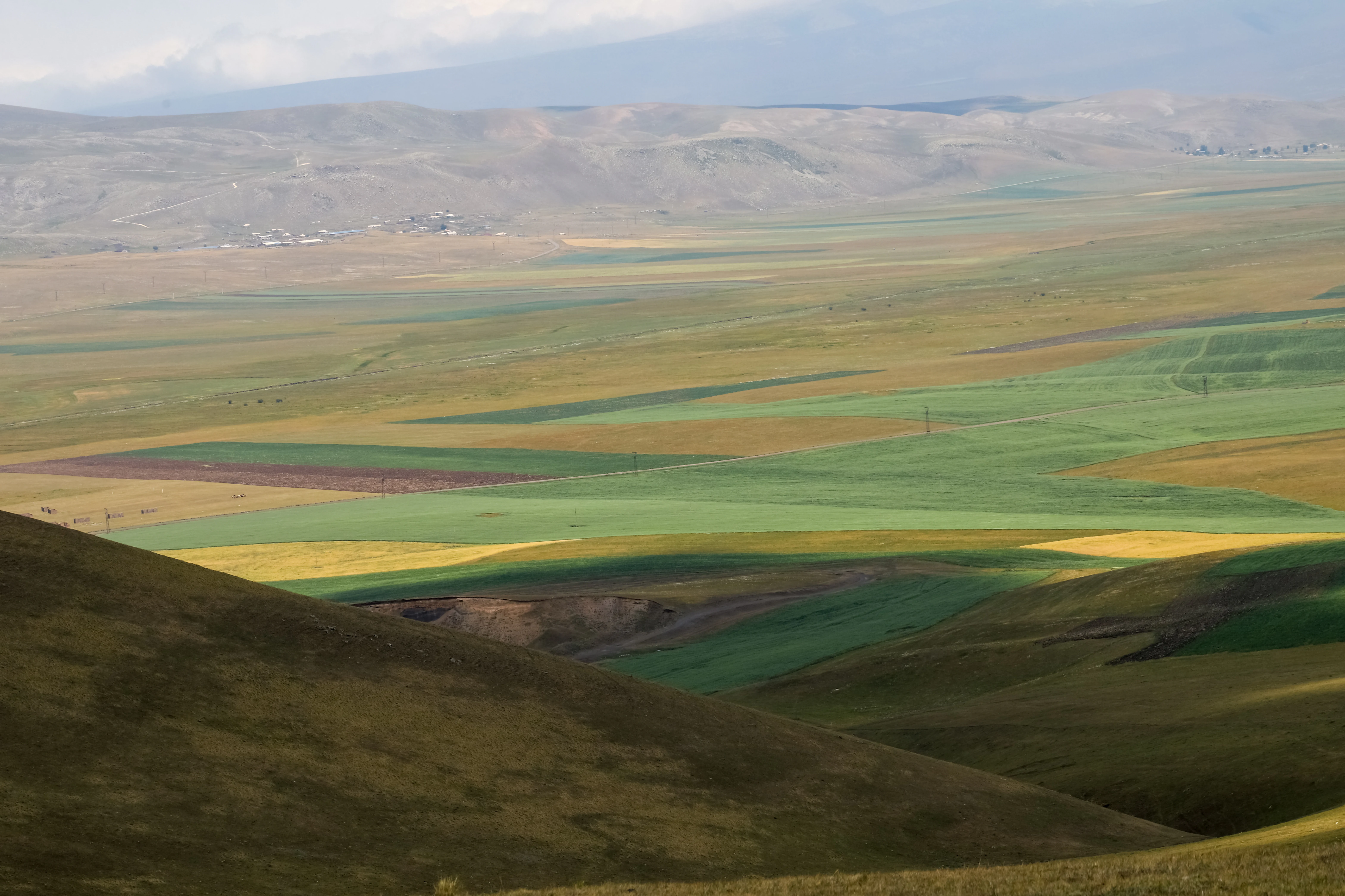 Wide view of rolling hills, colorful agricultural fields, and distant mountains in Lake Arpi National Park