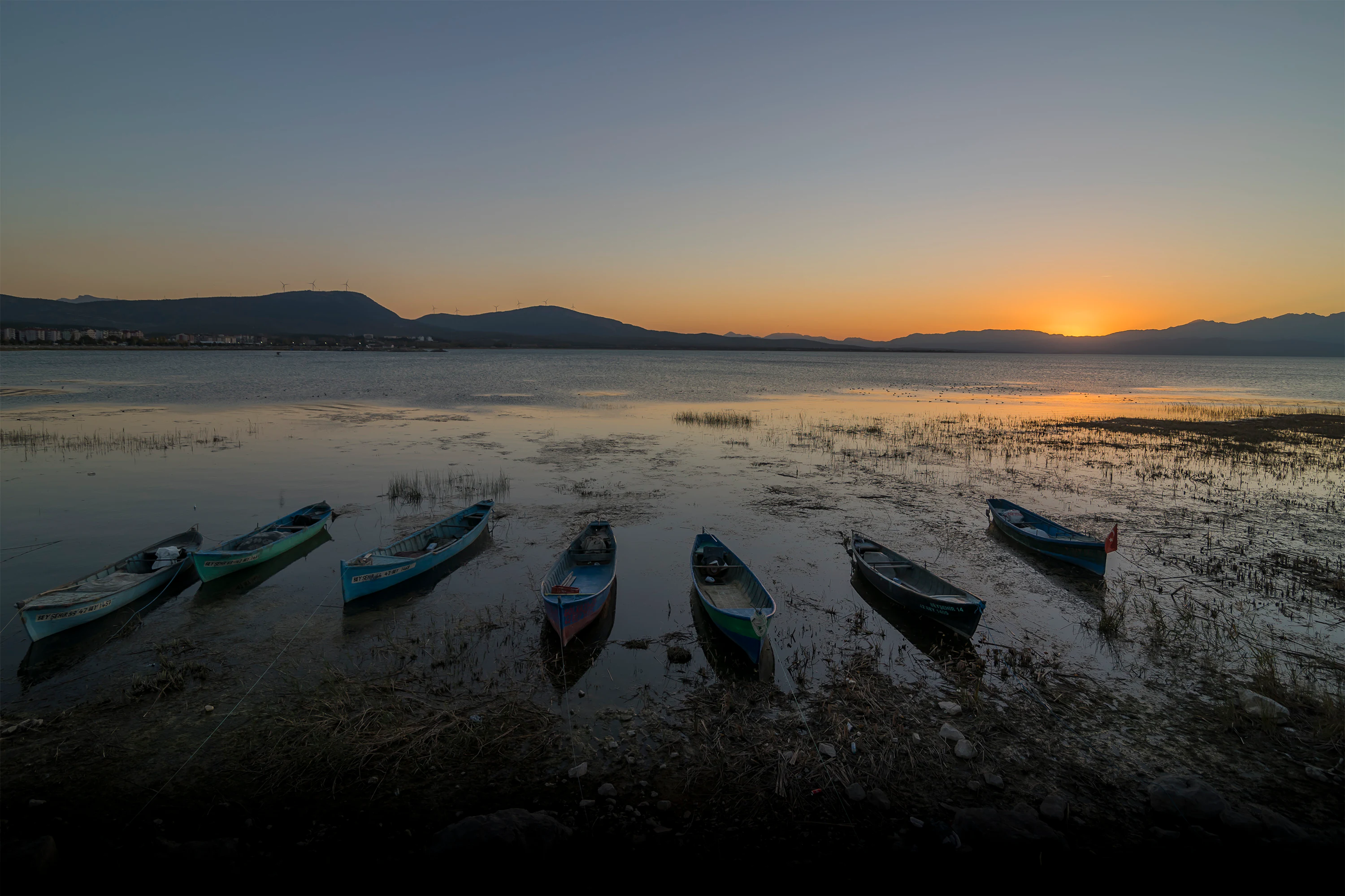 Fishing boats on the shore of Lake Beyşehir with a sunset sky and distant mountains