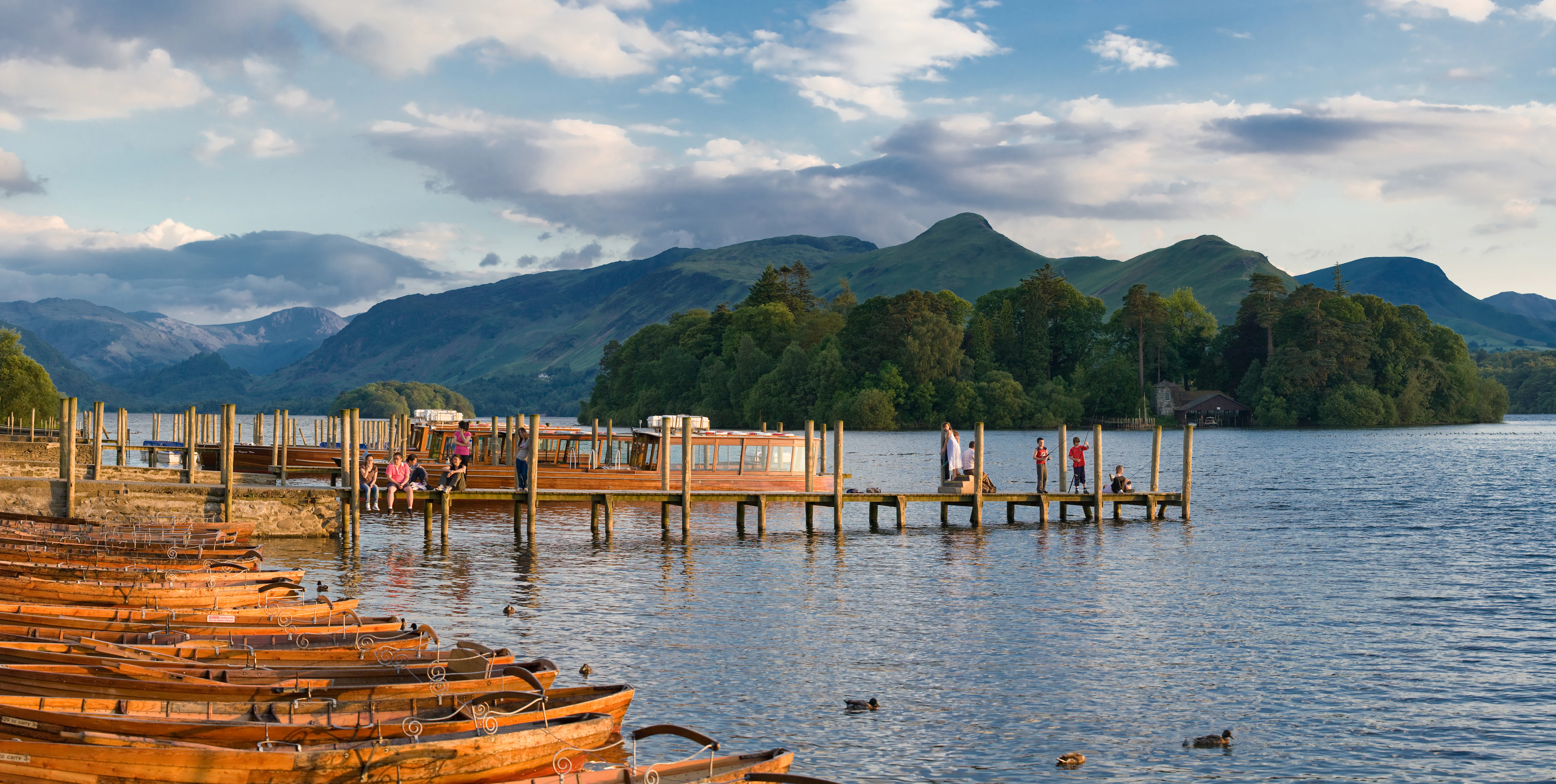 Wooden boats docked at a pier on Derwent Water with mountains visible in the background