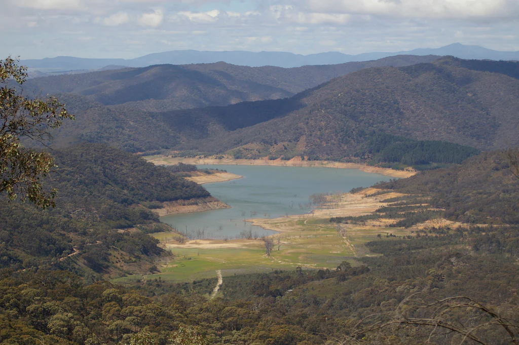 Panoramic view of Lake Eildon with surrounding hills and mountains under a partly cloudy sky.