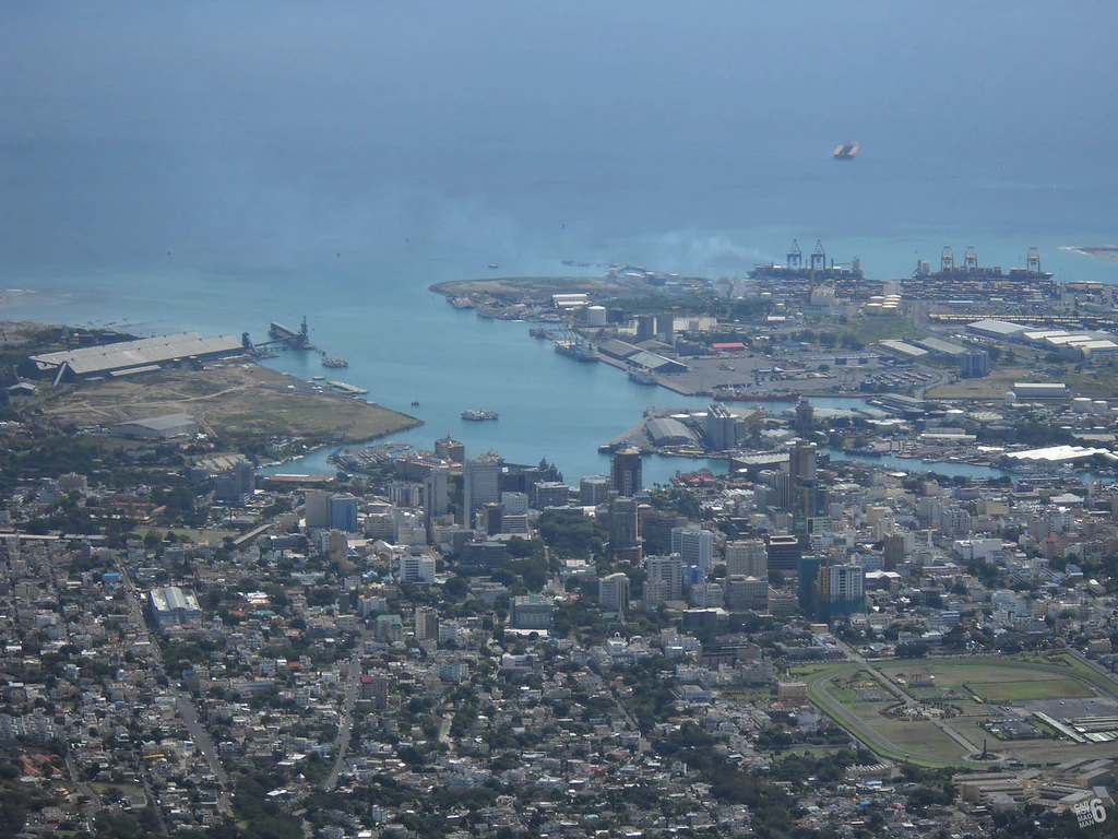 Una vista aérea elevada y de gran angular del paisaje urbano de Port Louis, el puerto y la costa, tomada desde la cima de una alta montaña.