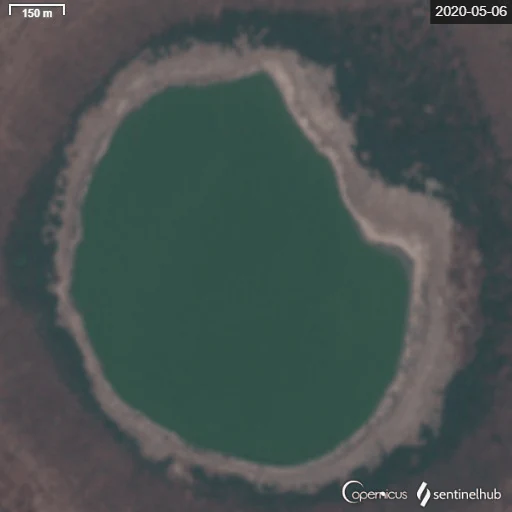 Satellite top down view of Lonar Lake circular crater filled with dark green water, surrounded by crater rims.