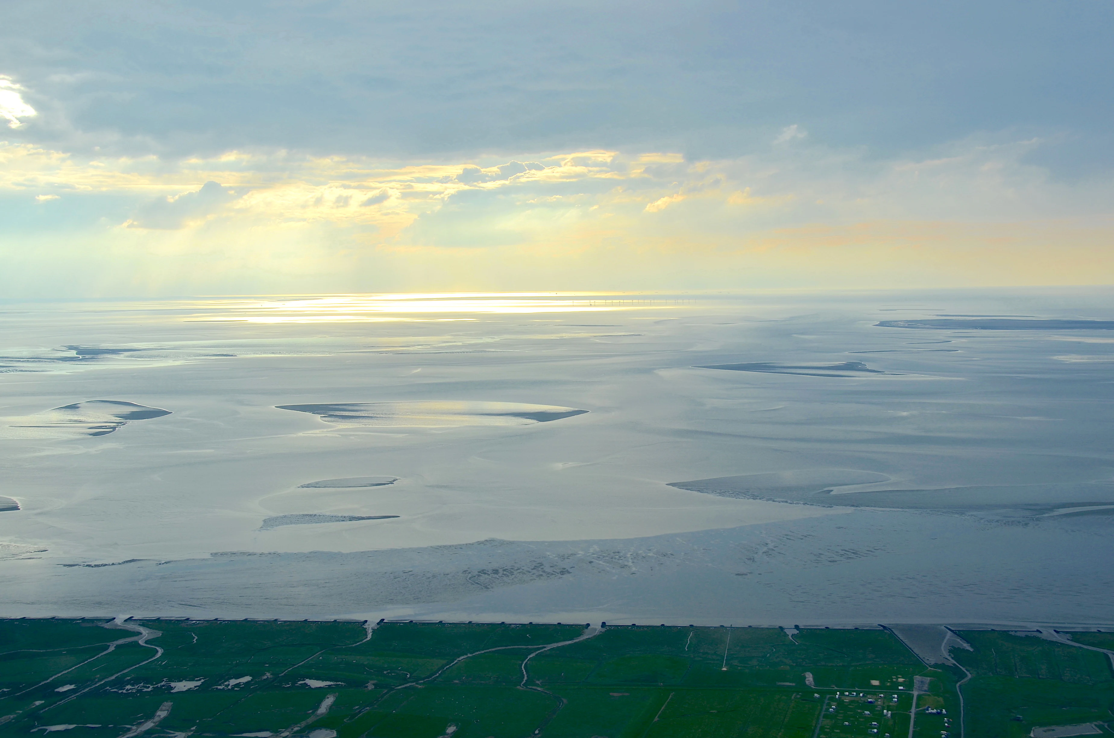 Aerial view showing extensive sandbanks and tidal flats in the Lower Saxon Wadden Sea National Park with coastal vegetation in the foreground