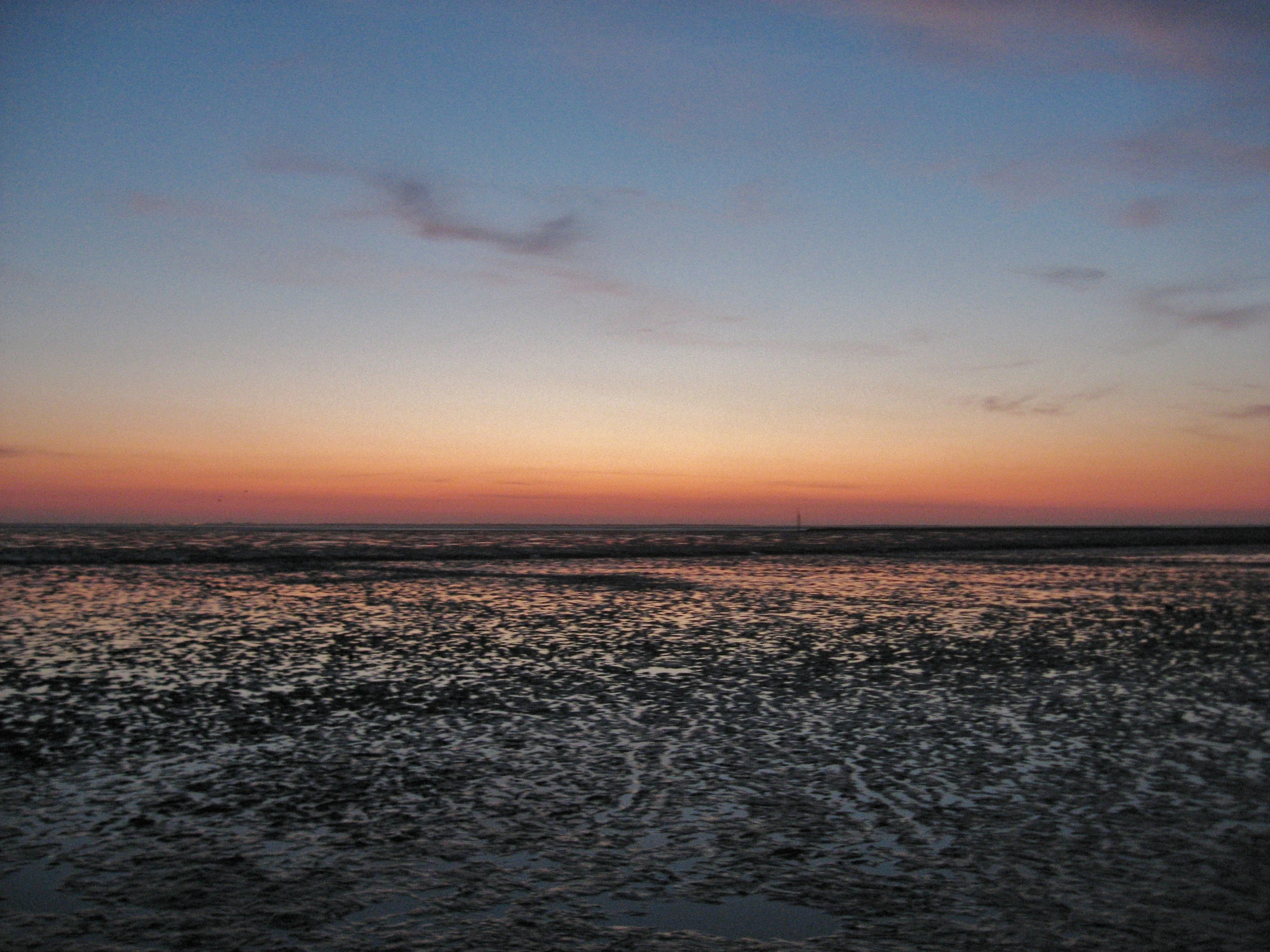 Sunset over the Wadden Sea with tidal flats and a gradient sky from orange to blue