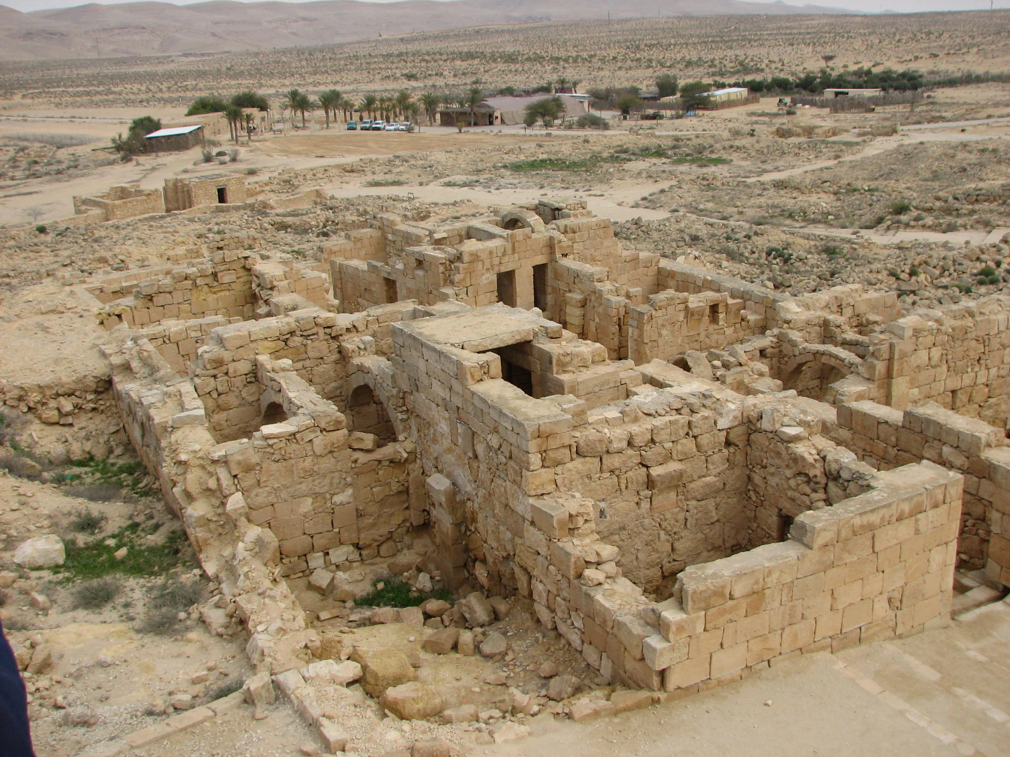 Ruinas de piedra de antiguas estructuras residenciales en un paisaje desértico con colinas distantes