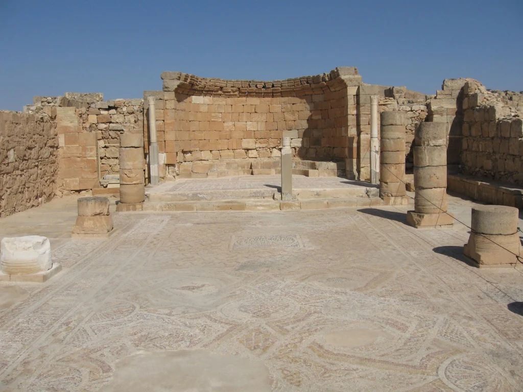 Antiguas ruinas de iglesias de piedra con suelos de mosaico y columnas bajo un cielo azul claro