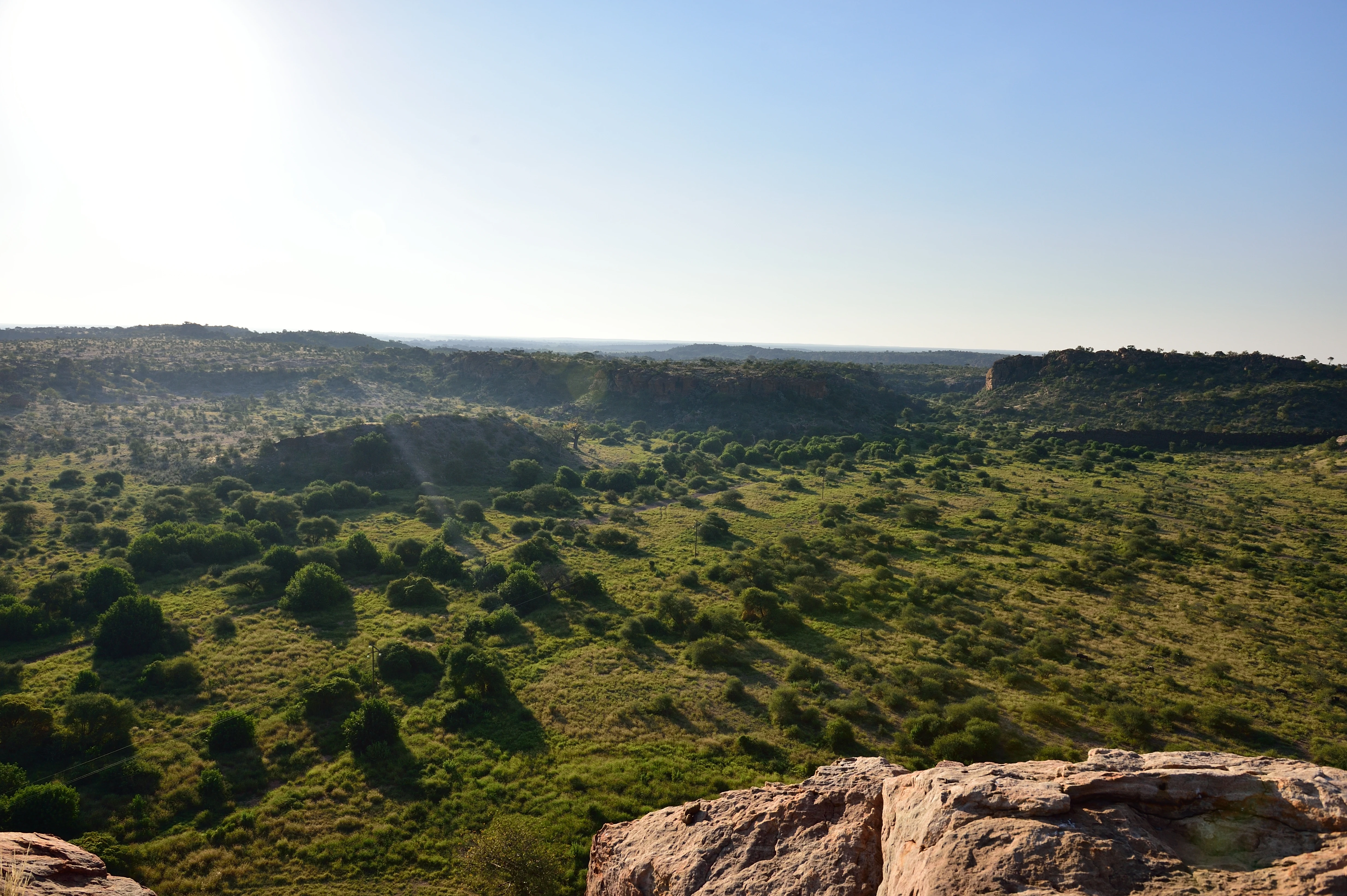 Amplio paisaje del valle del río Limpopo con vegetación de sabana verde y afloramientos rocosos bajo un cielo azul claro