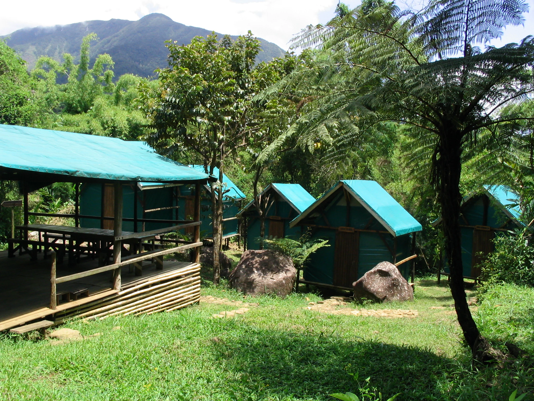 Small huts with green roofs at Camp Mantella in Marojejy National Park, surrounded by lush vegetation and mountains