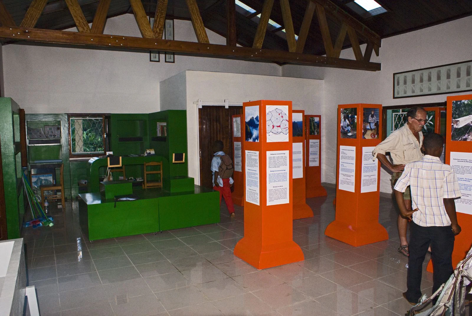 Interior of an interpretation center with green walls, orange display stands, and people viewing exhibits