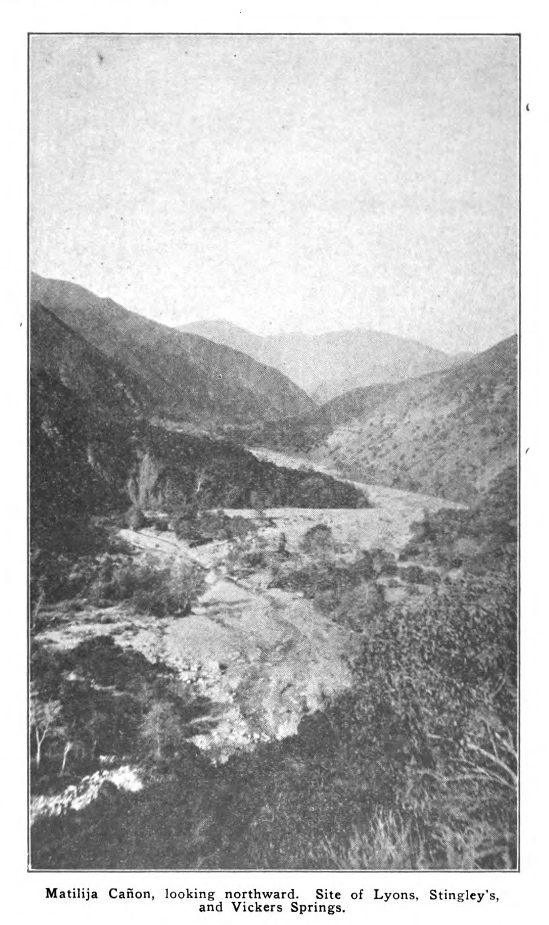 A black and white archival photograph looking north into a steep, rugged canyon with a rocky creek bed at the base, surrounded by scrub-covered mountain slopes.