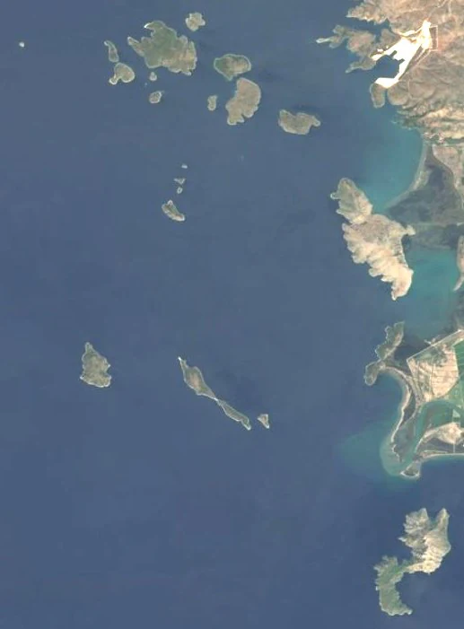 Imagen satelital cenital que muestra un grupo de islas en un mar azul profundo a lo largo de una costa irregular.