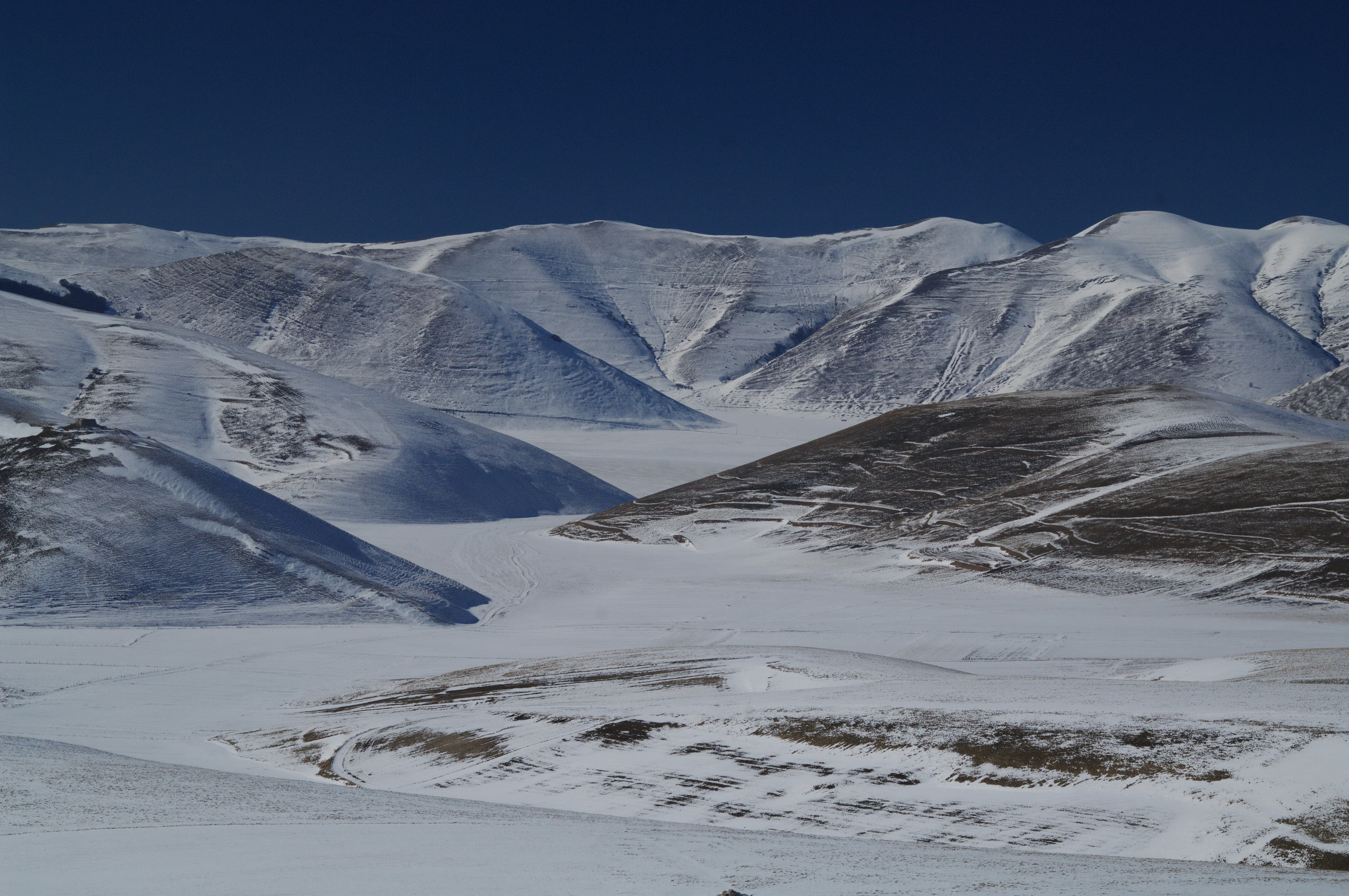 Snow-covered mountain plateau with rugged peaks under clear blue sky