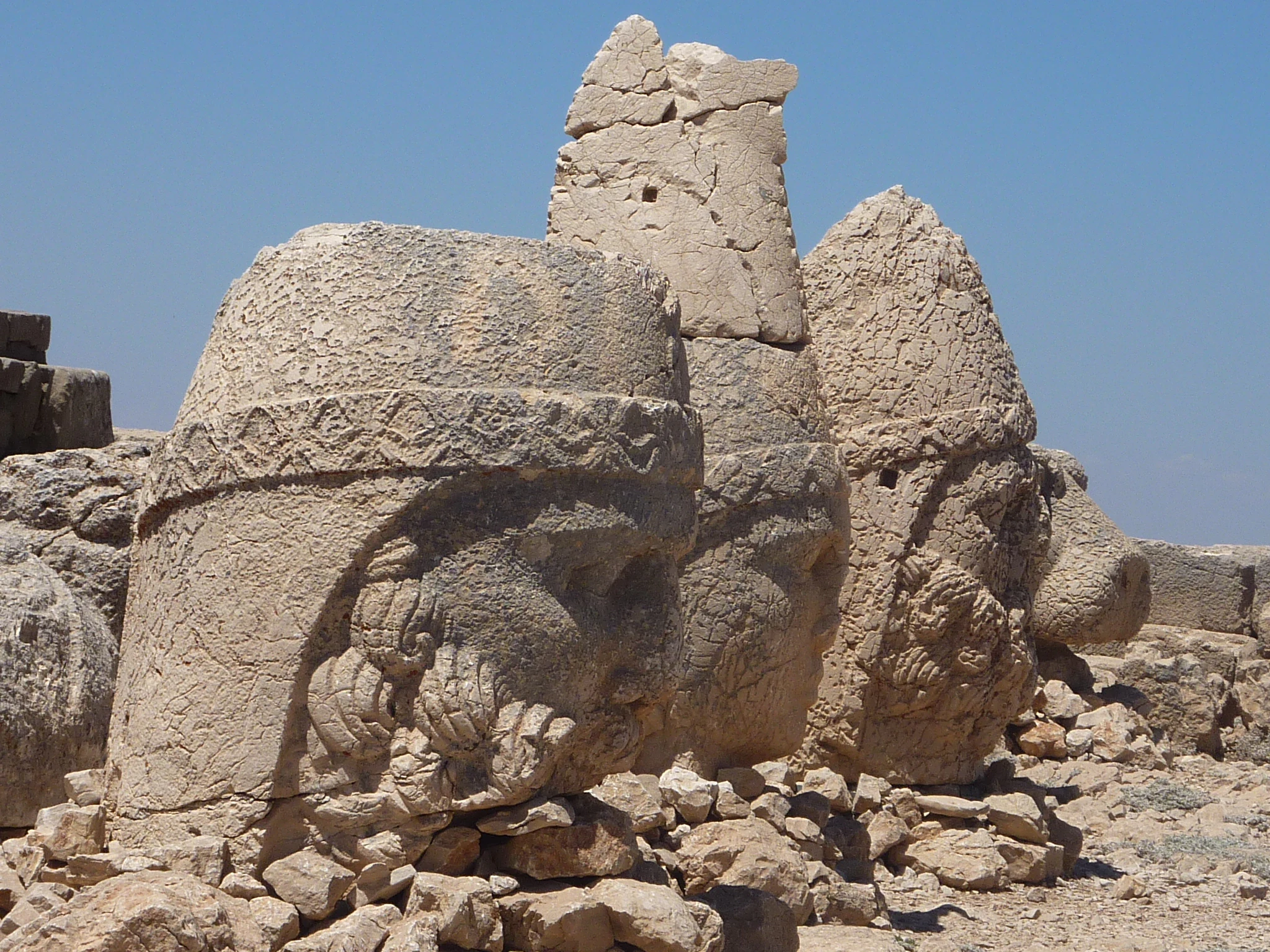 Large carved stone heads of ancient statues on a rocky mountain summit
