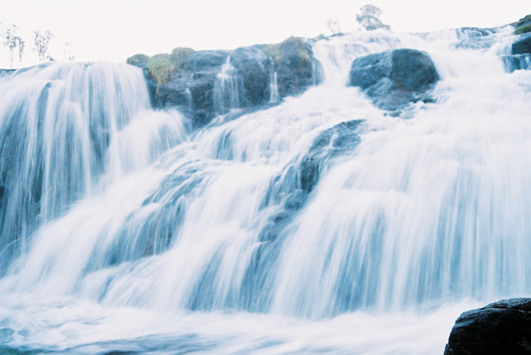 A multi-tiered waterfall cascading down rocky formations with flowing water