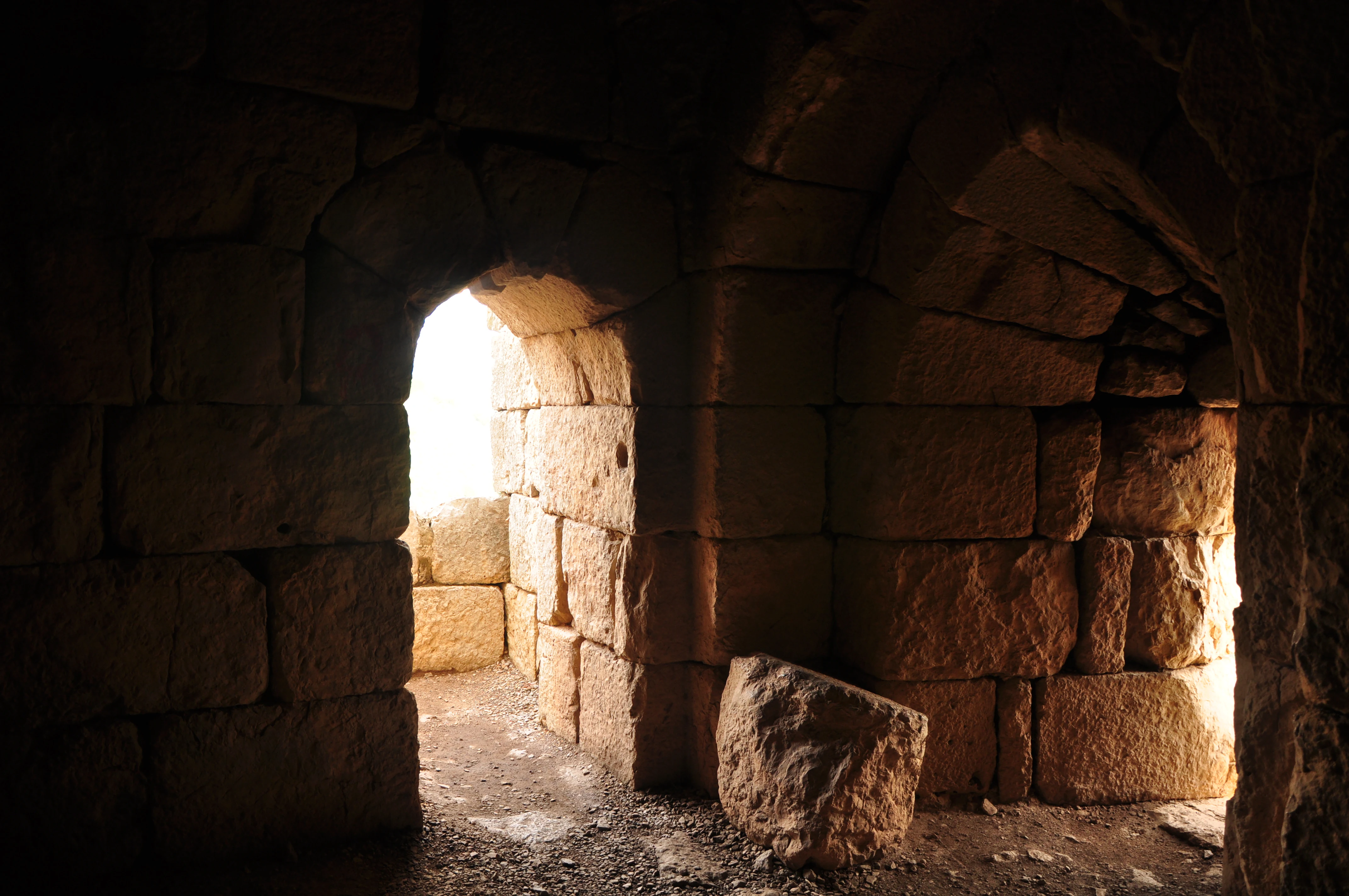 Stone interior room with arched openings showing light from an exterior space