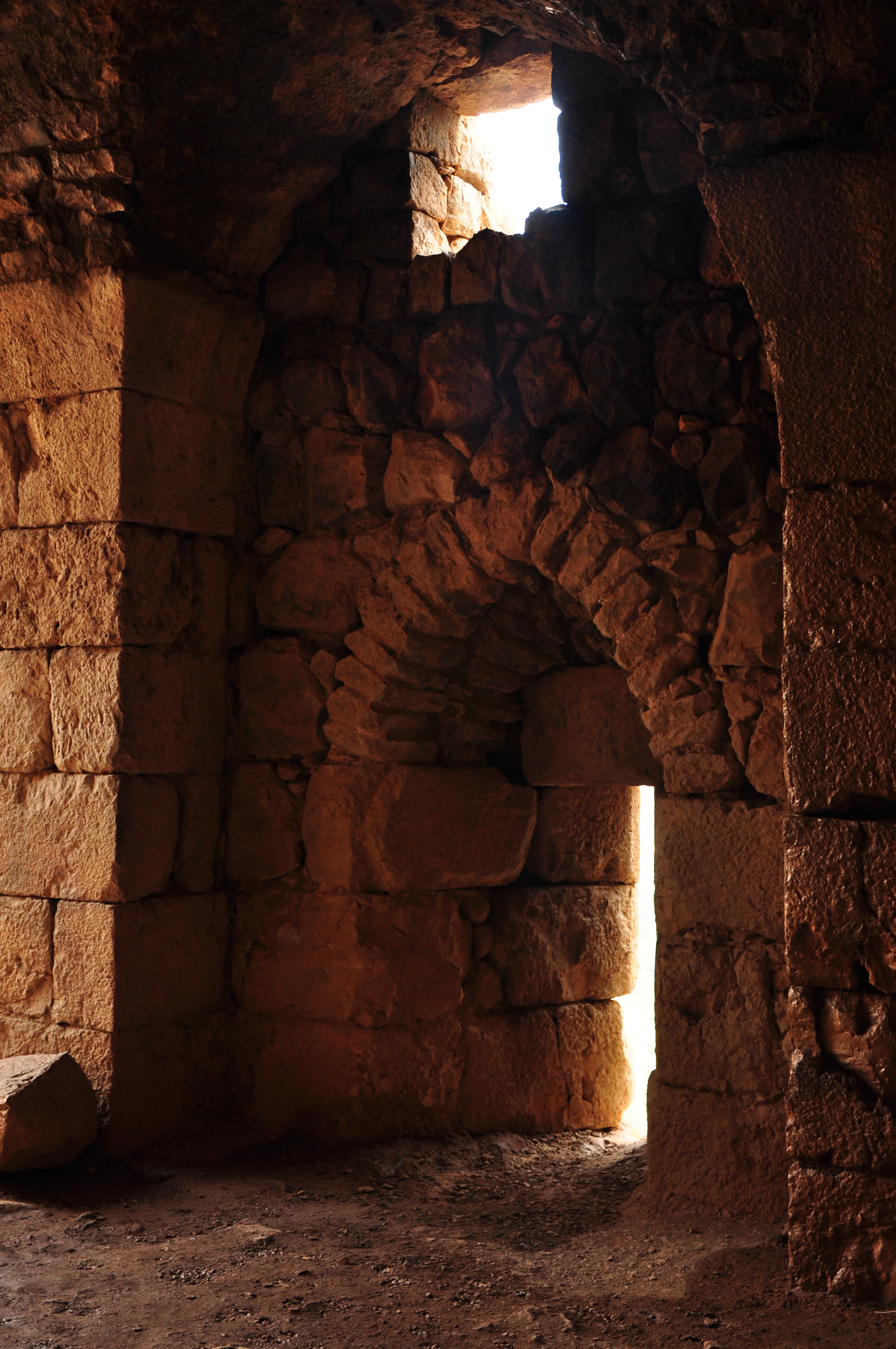 Stone archway with light streaming through an opening in a historic fortress interior