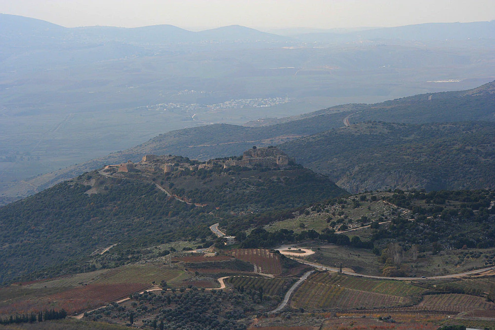 Wide landscape view of Nimrod Fortress on a hilltop with surrounding valleys and hills under overcast sky