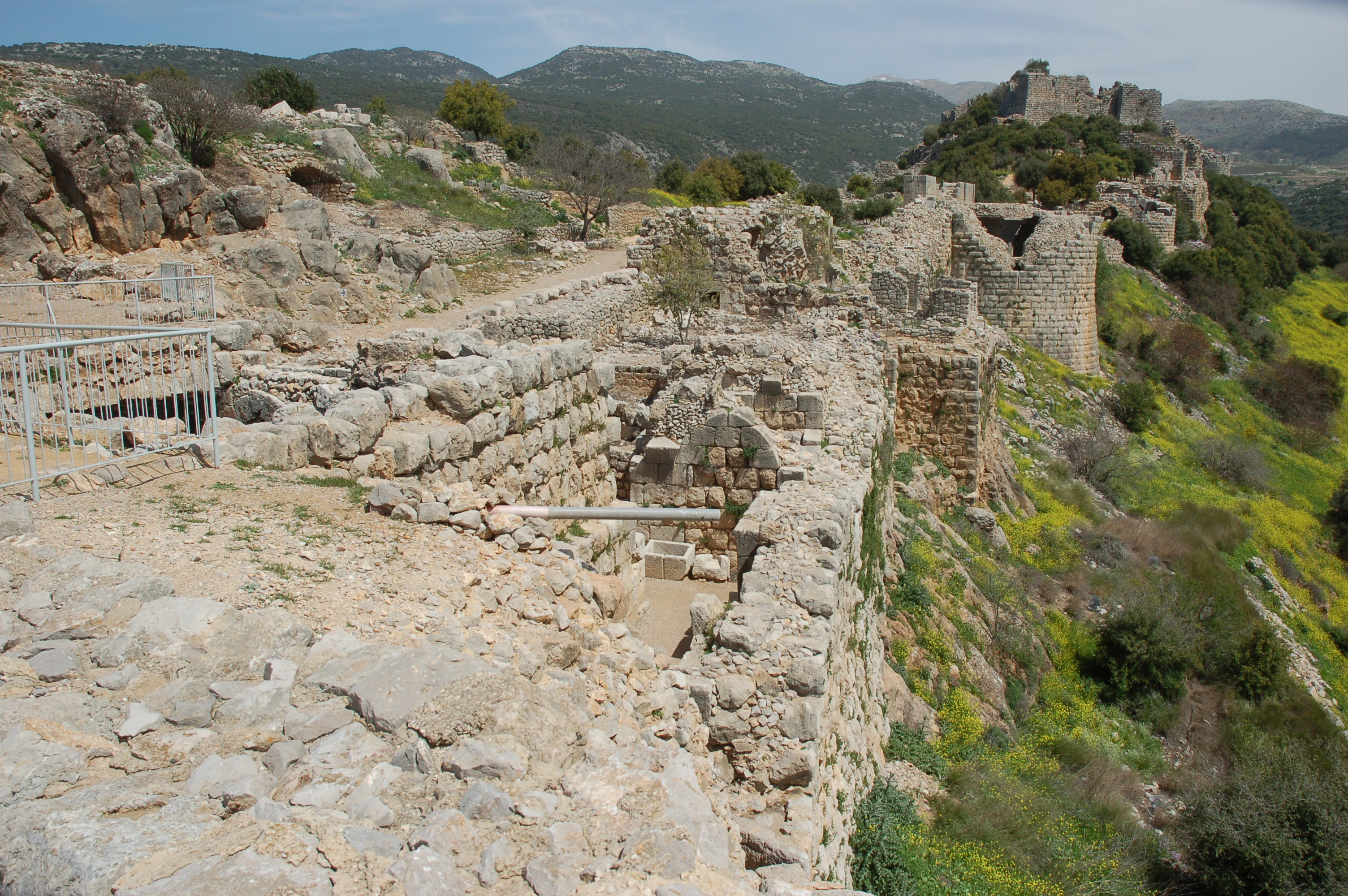 Stone ruins of Nimrod Fortress on a hillside with green vegetation and distant mountains