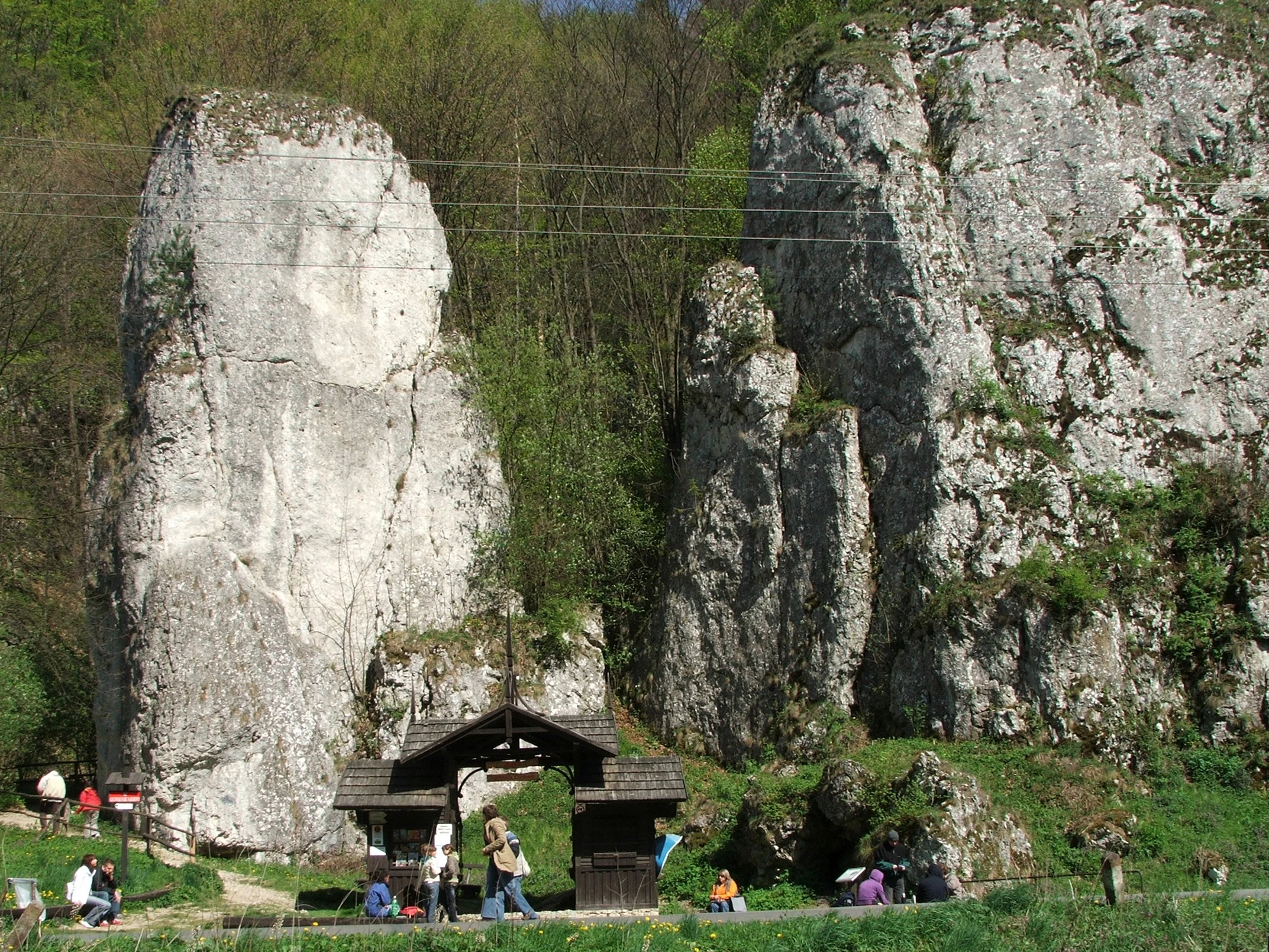 Limestone rock formation with wooden shelter and visitors in Ojców National Park