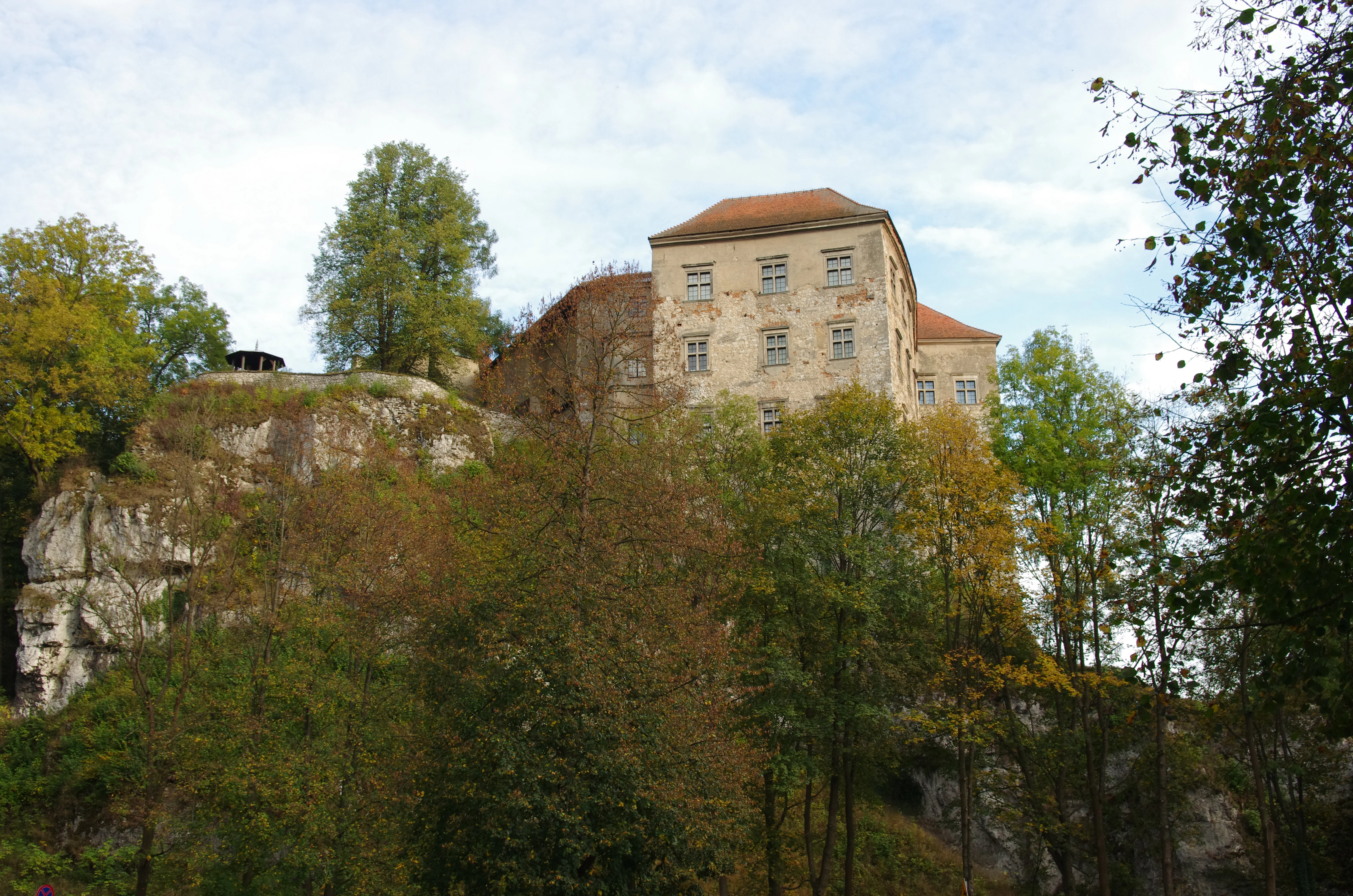 Pieskowa Skała Castle on a rocky cliff surrounded by forest with autumn-colored trees