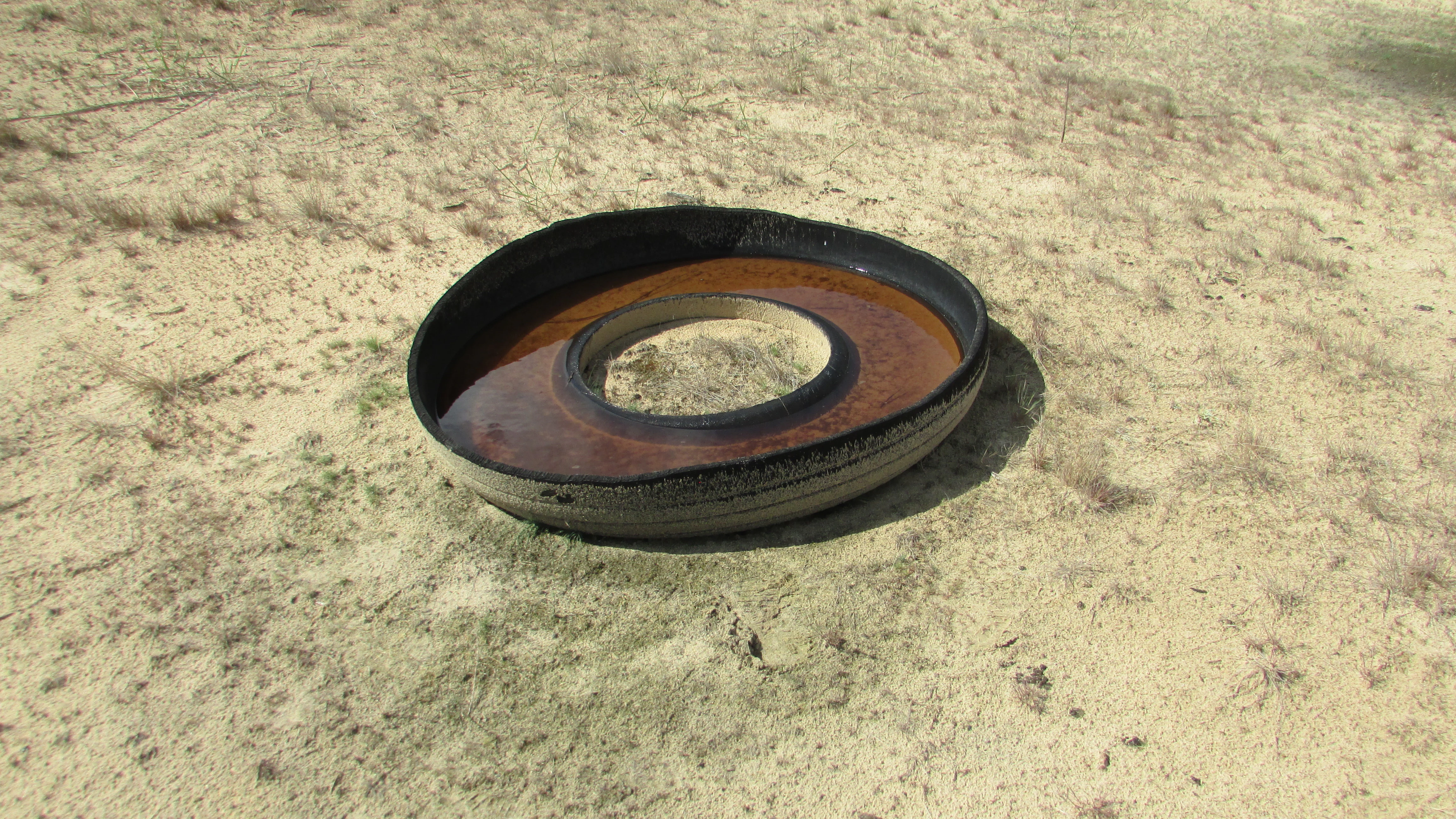 Circular drinking bowl filled with water on sandy ground in a desert landscape