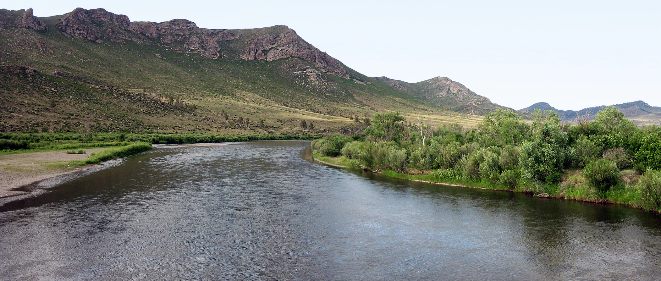 River flowing through a valley surrounded by green vegetation and distant mountains