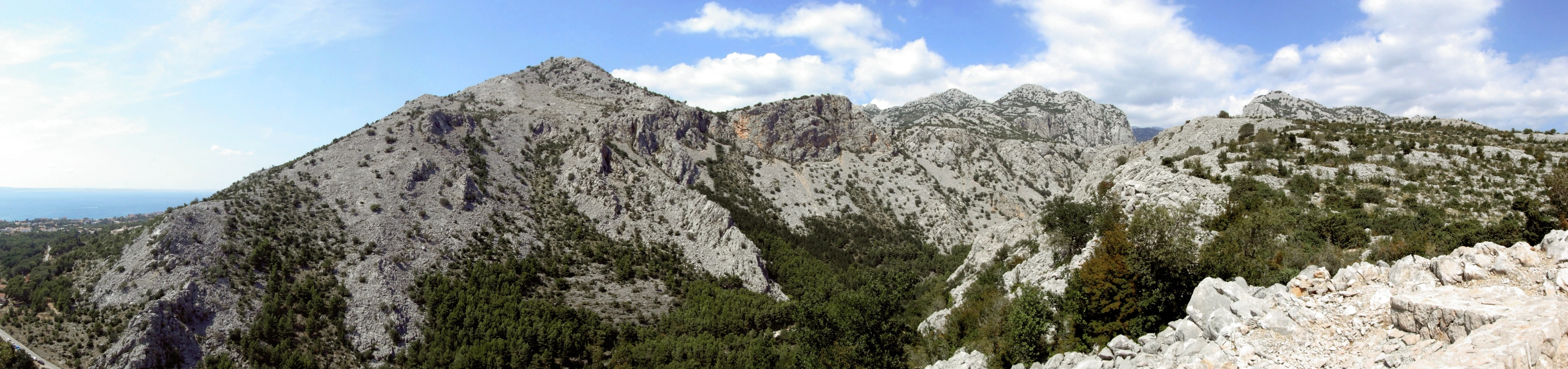 Panoramic view of Velika Paklenica canyon showing rocky mountain peaks, forested valleys, and clear blue sky