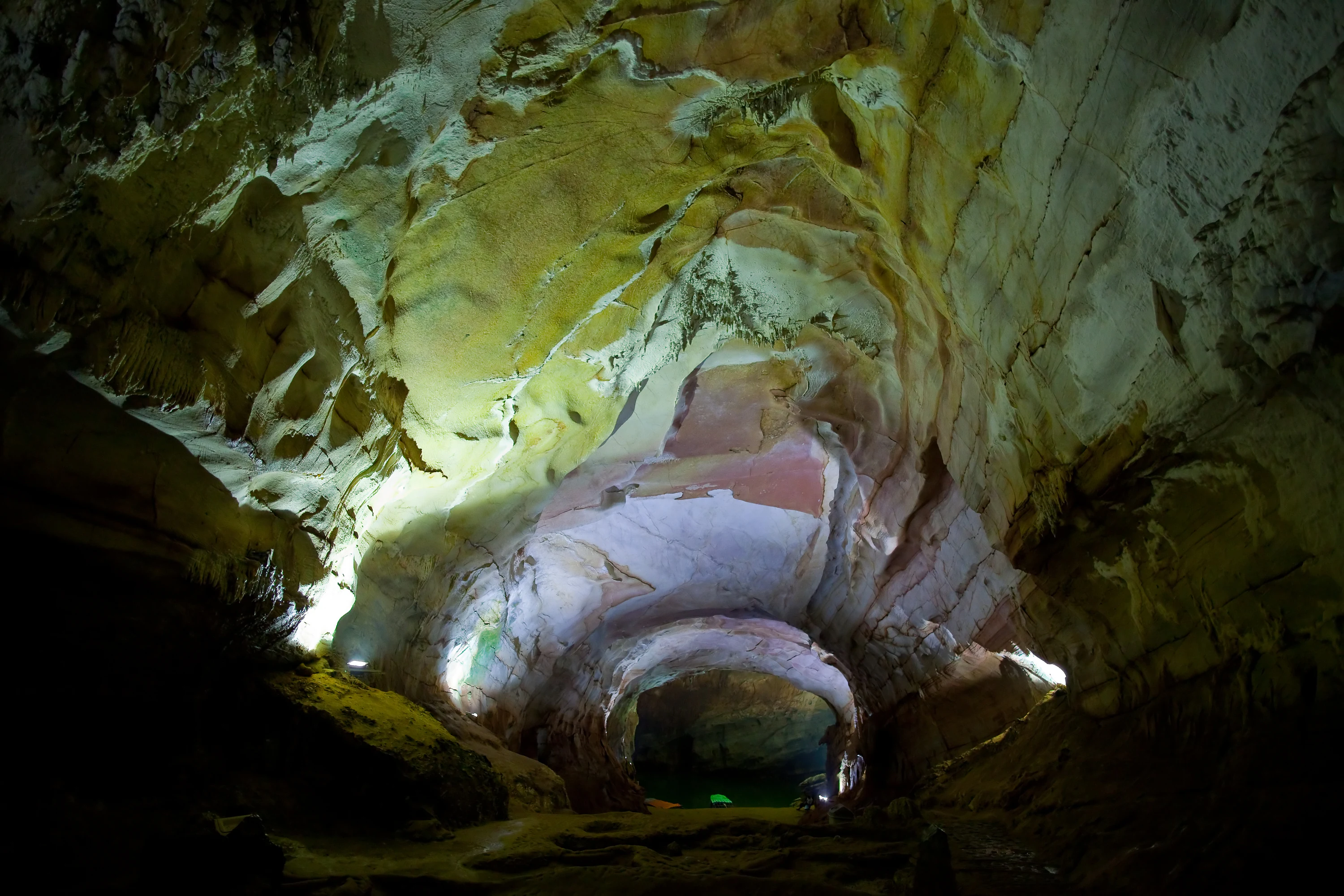 Formaciones rocosas en el interior de una cueva con iluminación artificial, que muestran texturas en capas y un pasaje que se adentra en la cueva