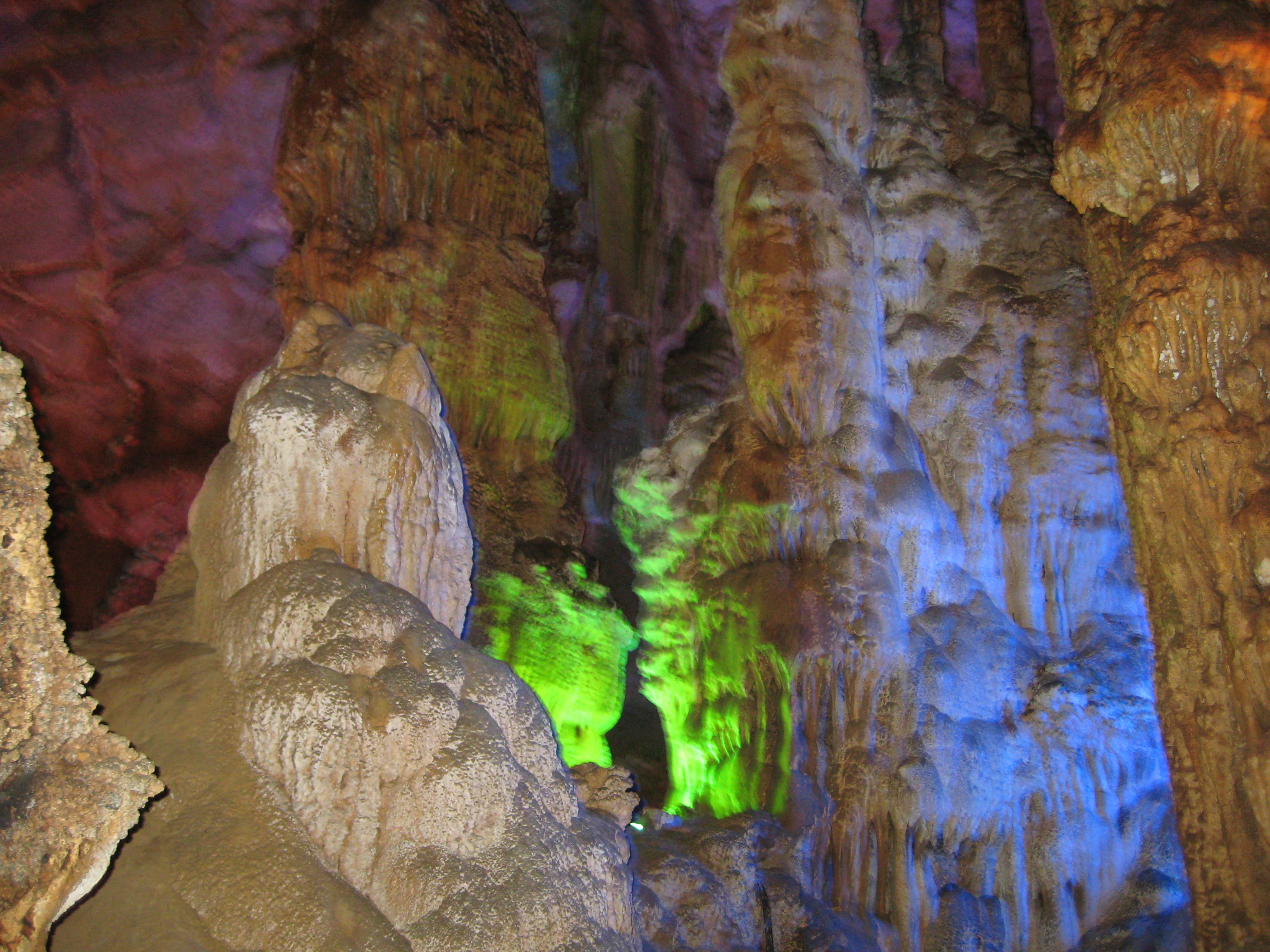 Interior de una cueva con estalactitas y estalagmitas de colores iluminados en el Parque Nacional Phong Nha-Kẻ Bàng