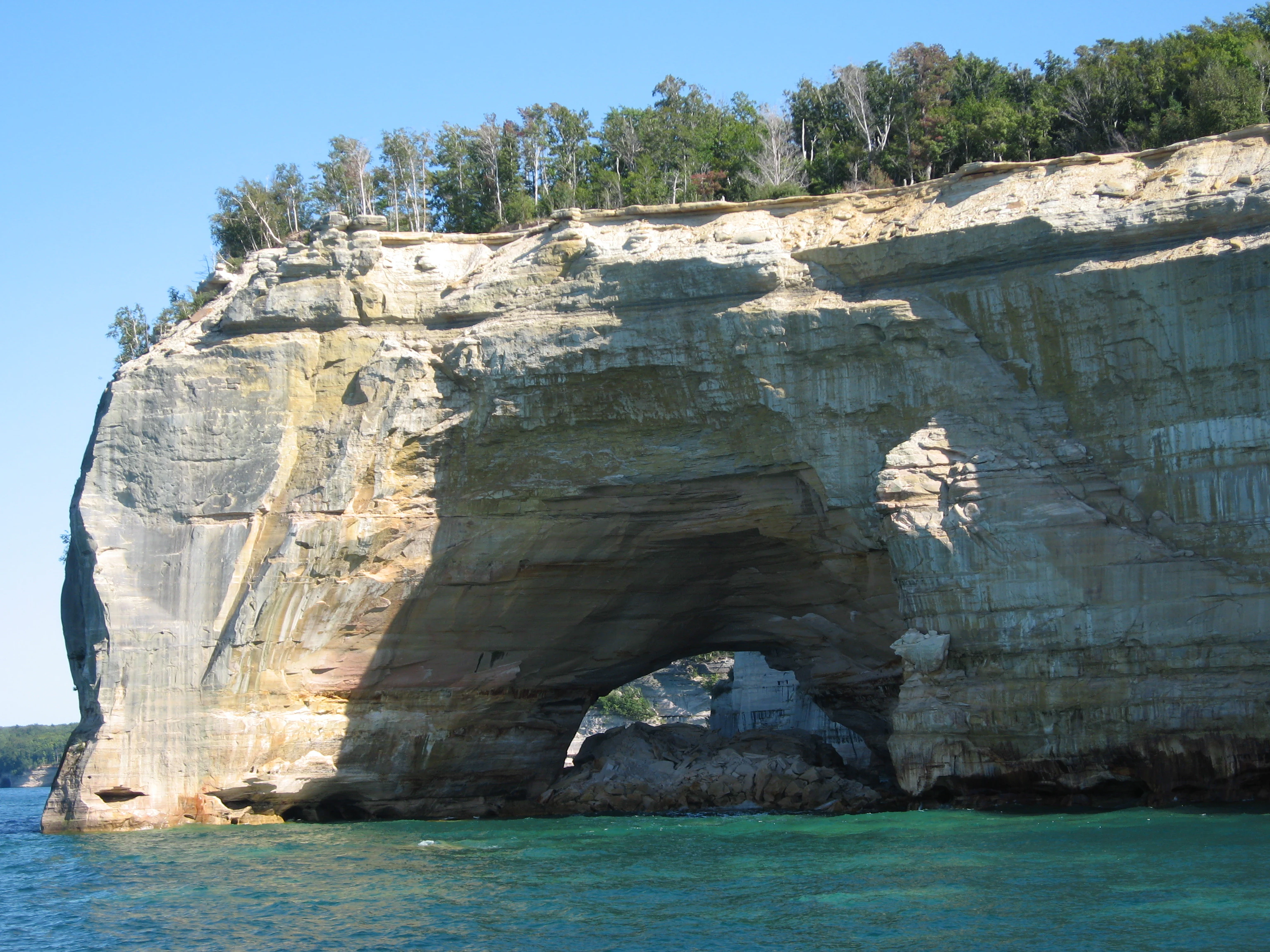 Una vista amplia del arco de arenisca Grand Portal que se alza sobre el agua en Pictured Rocks National Lakeshore.
