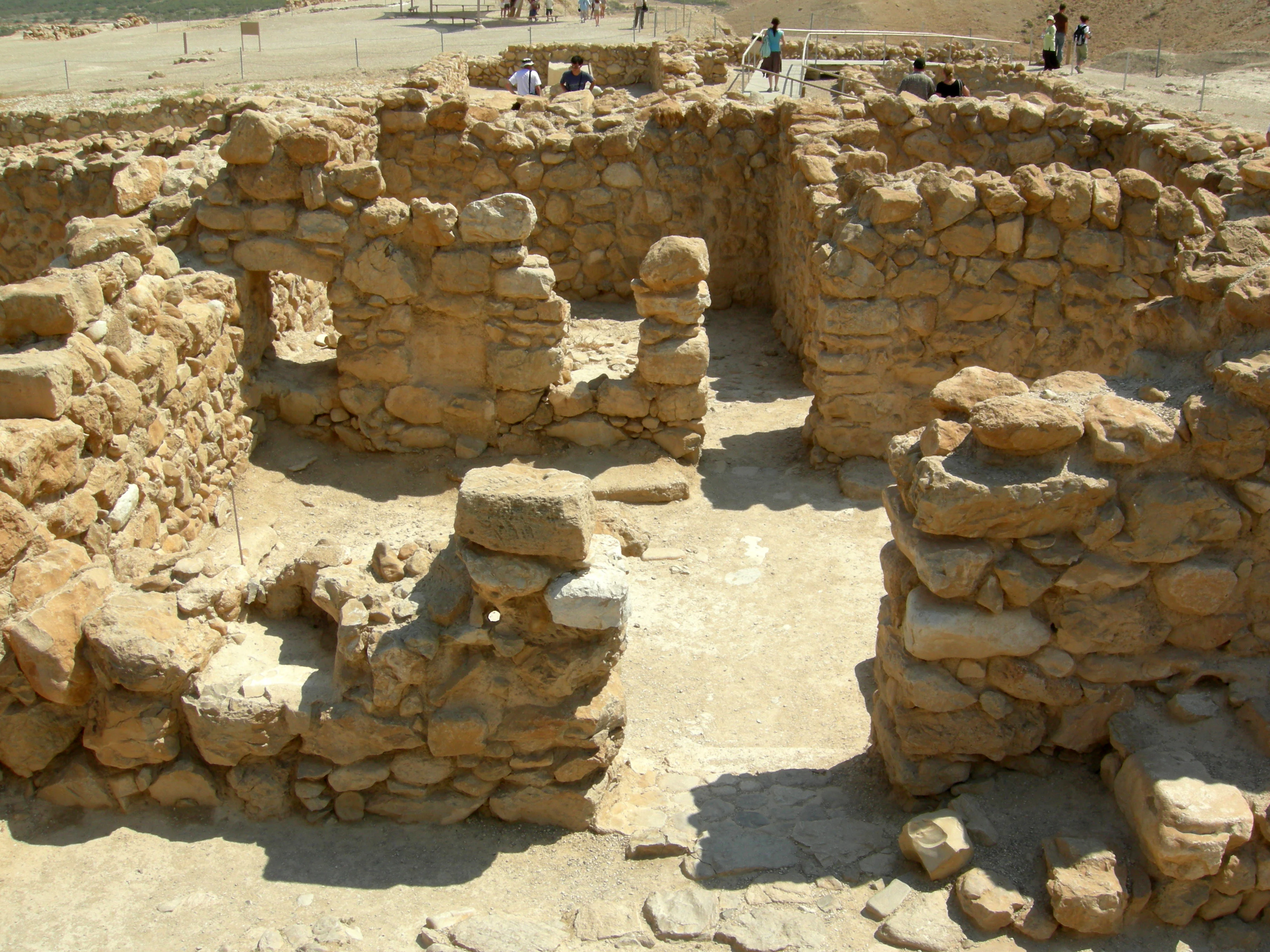Stone ruins of ancient living quarters with open courtyards and walls in Qumran National Park