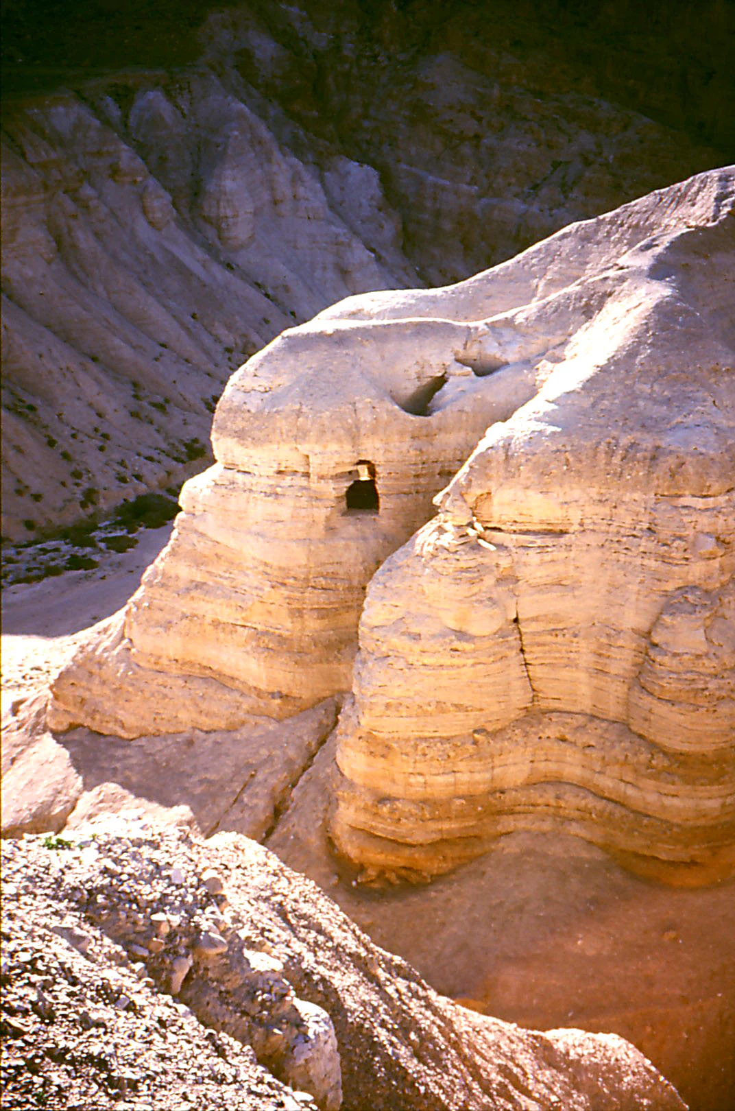 A rocky desert landscape with layered sedimentary rock formations and caves