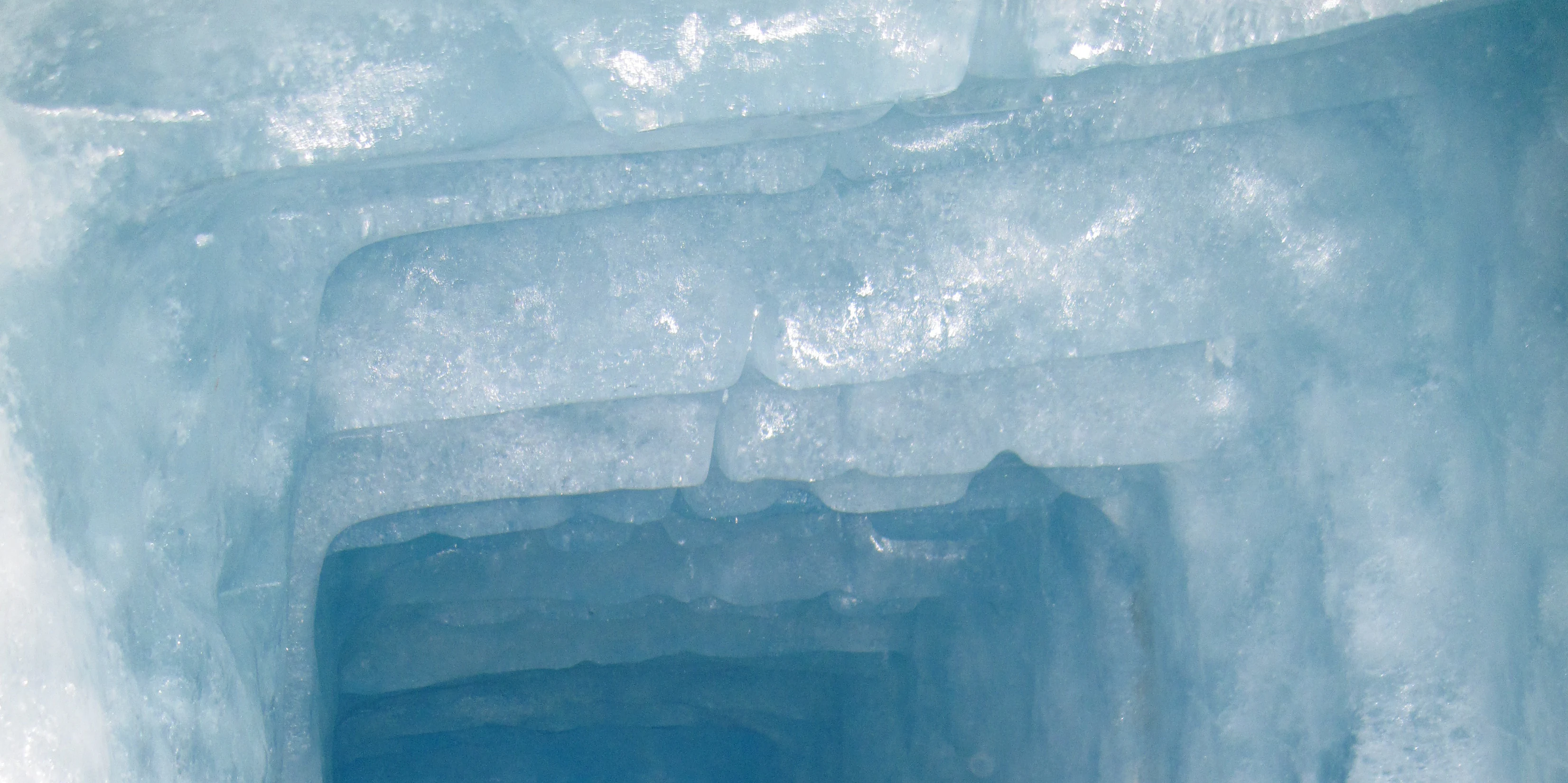 Close up view of translucent deep blue ice formations inside a glacial cave.