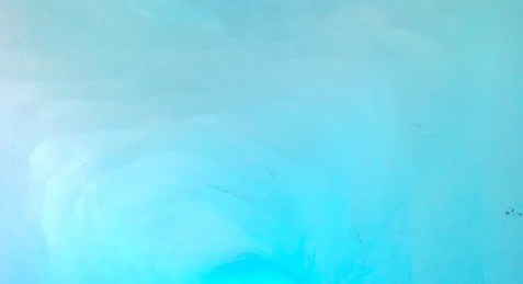 A close-up, abstract view of vibrant, translucent light-blue glacial ice.