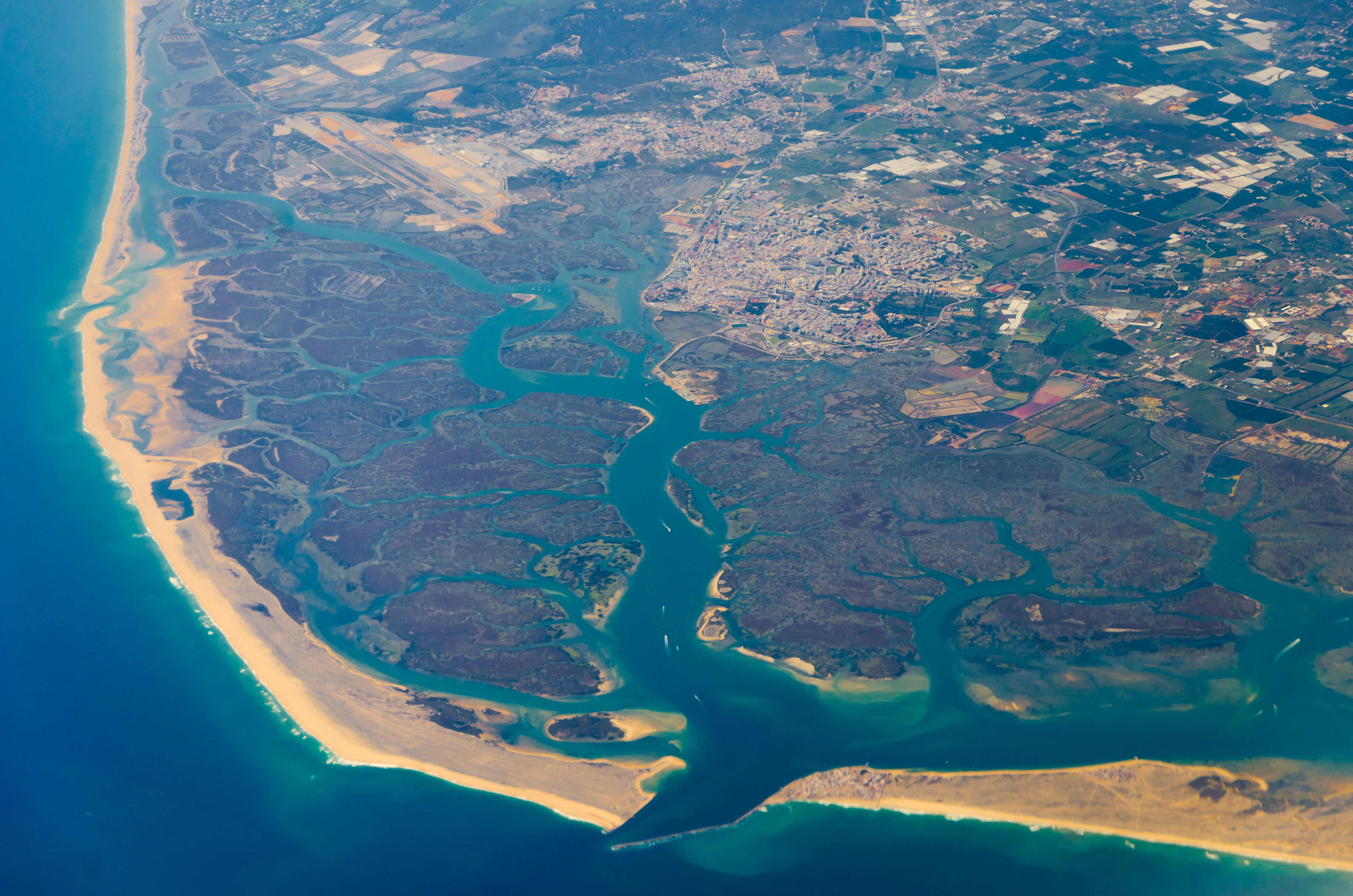 Aerial view showing coastal lagoons, sand dunes, and urban areas adjacent to the coast