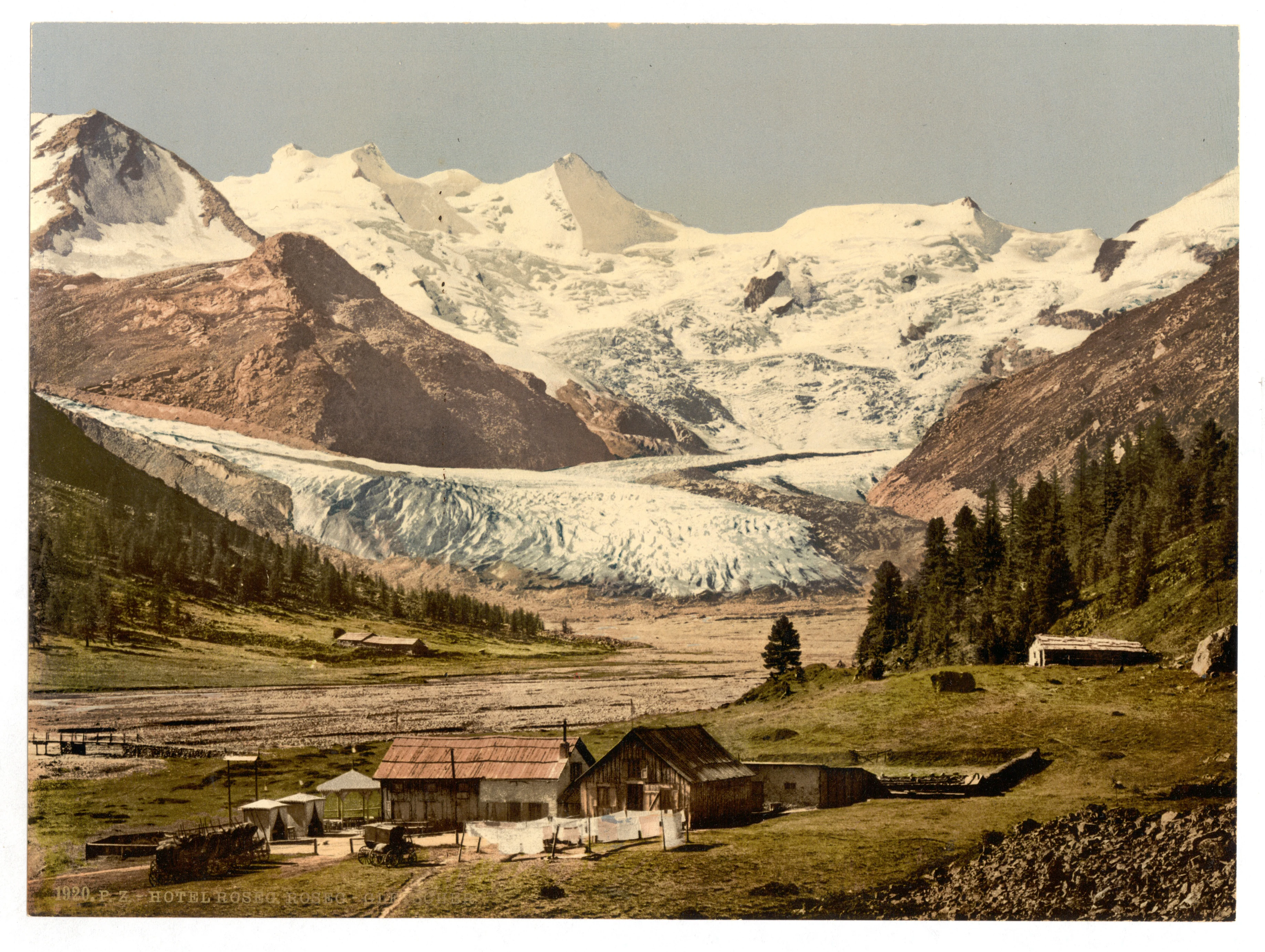 A vintage colorized image showing a large glacier flowing down from snow-capped mountains into a valley, with wooden buildings in the foreground.