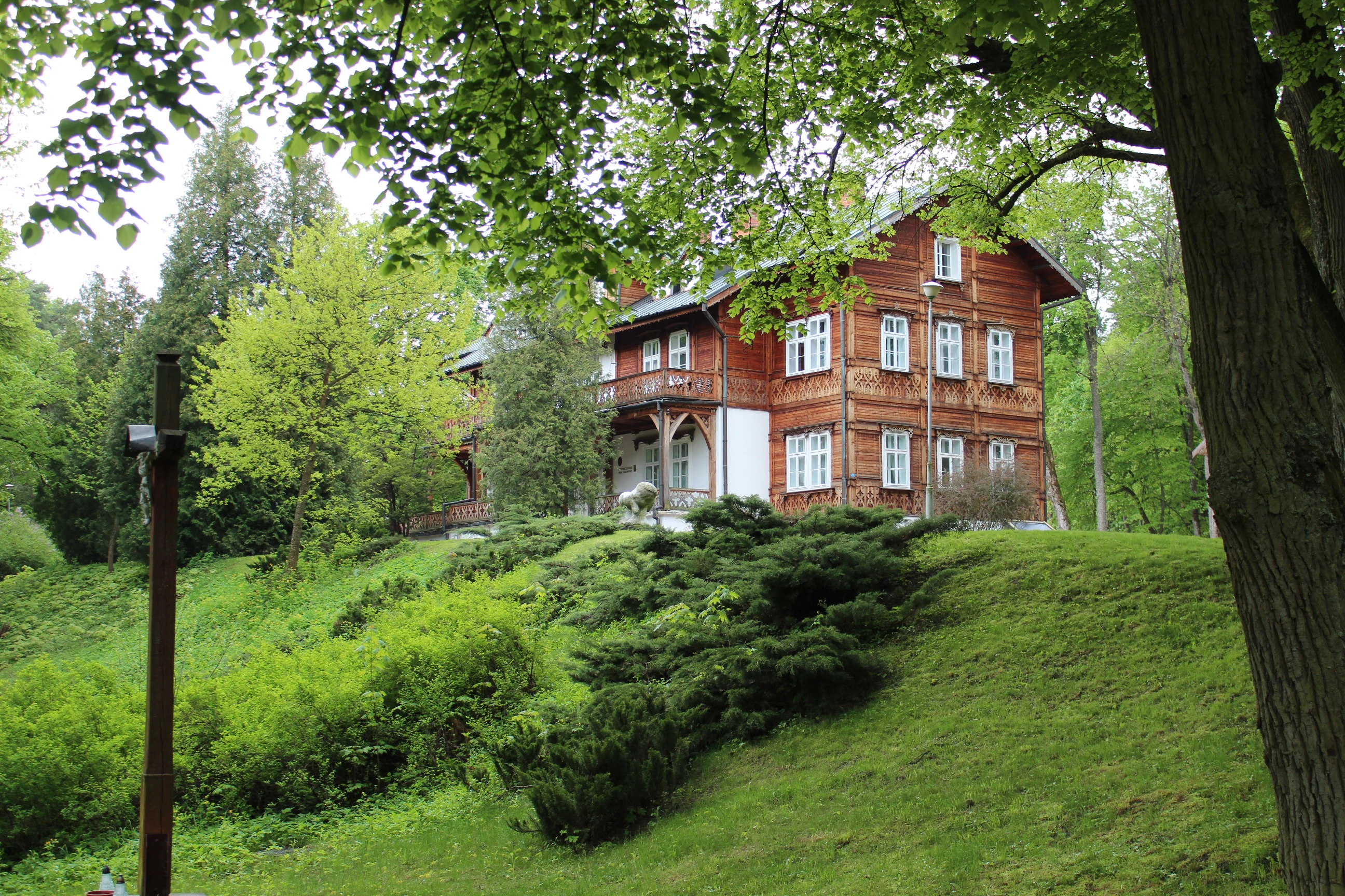 Red wooden house on a grassy hill with green trees and shrubs in a national park setting
