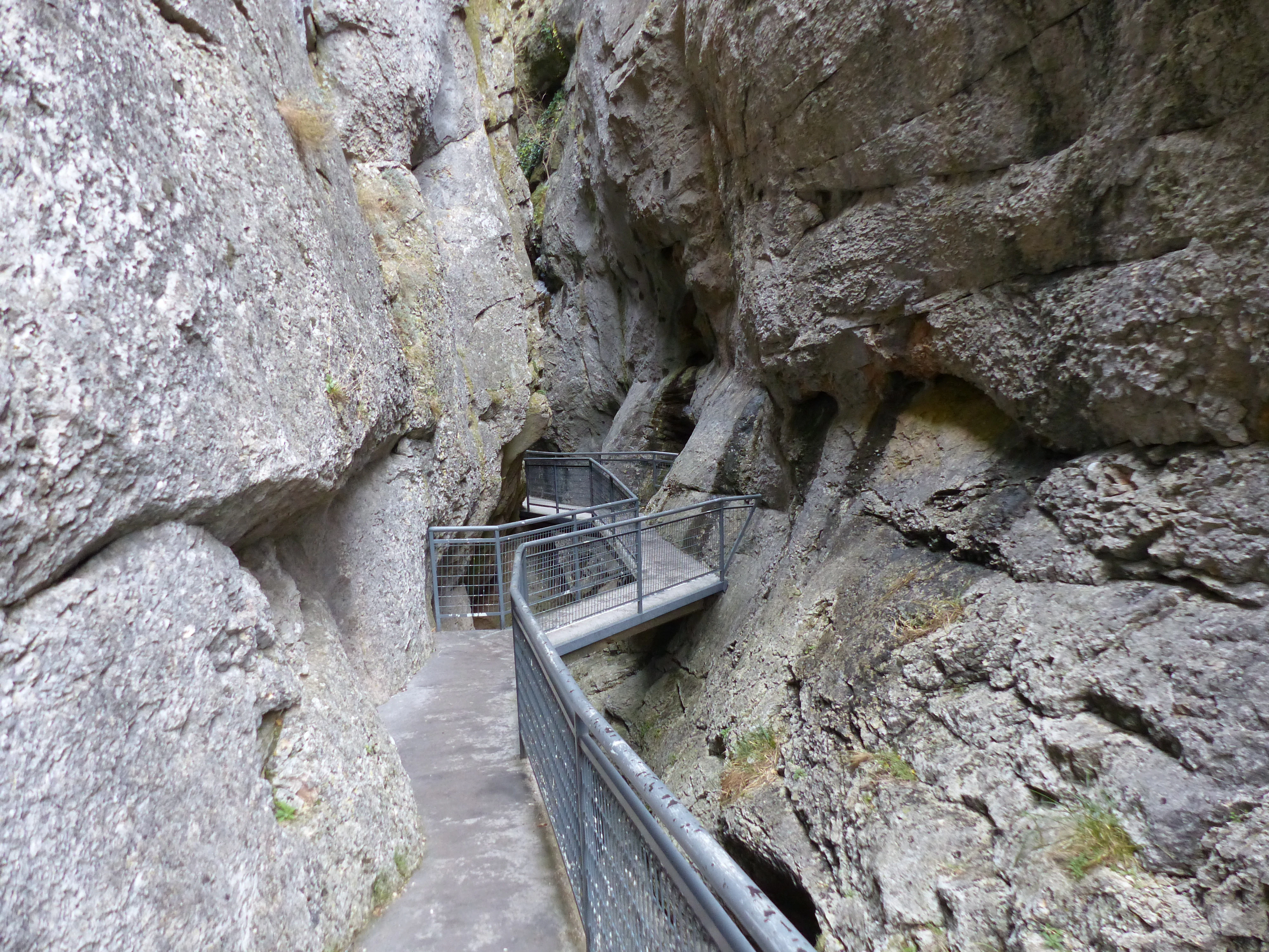 A metal boardwalk trail snakes through a very narrow, high-walled limestone gorge in Sabinares del Arlanza-La Yecla Natural Park.